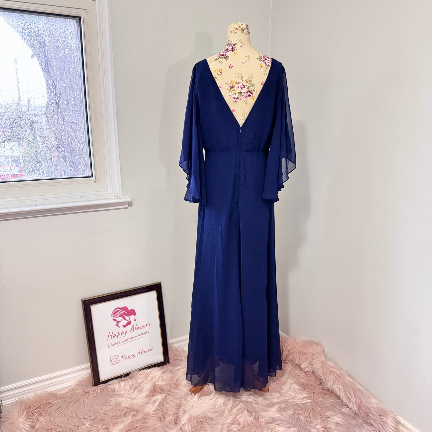 Turn heads in this stunning deep navy gown that radiates elegance and grace. Designed with a flowy chiffon overlay, a flattering cinched waist, and dreamy flutter sleeves, this dress is perfect for formal events, weddings, or special occasions. The deep V-neckline and subtle front slit add just the right touch of sophistication and allure. This gently cherished piece is in excellent condition, ready for a new owner to make unforgettable memories.