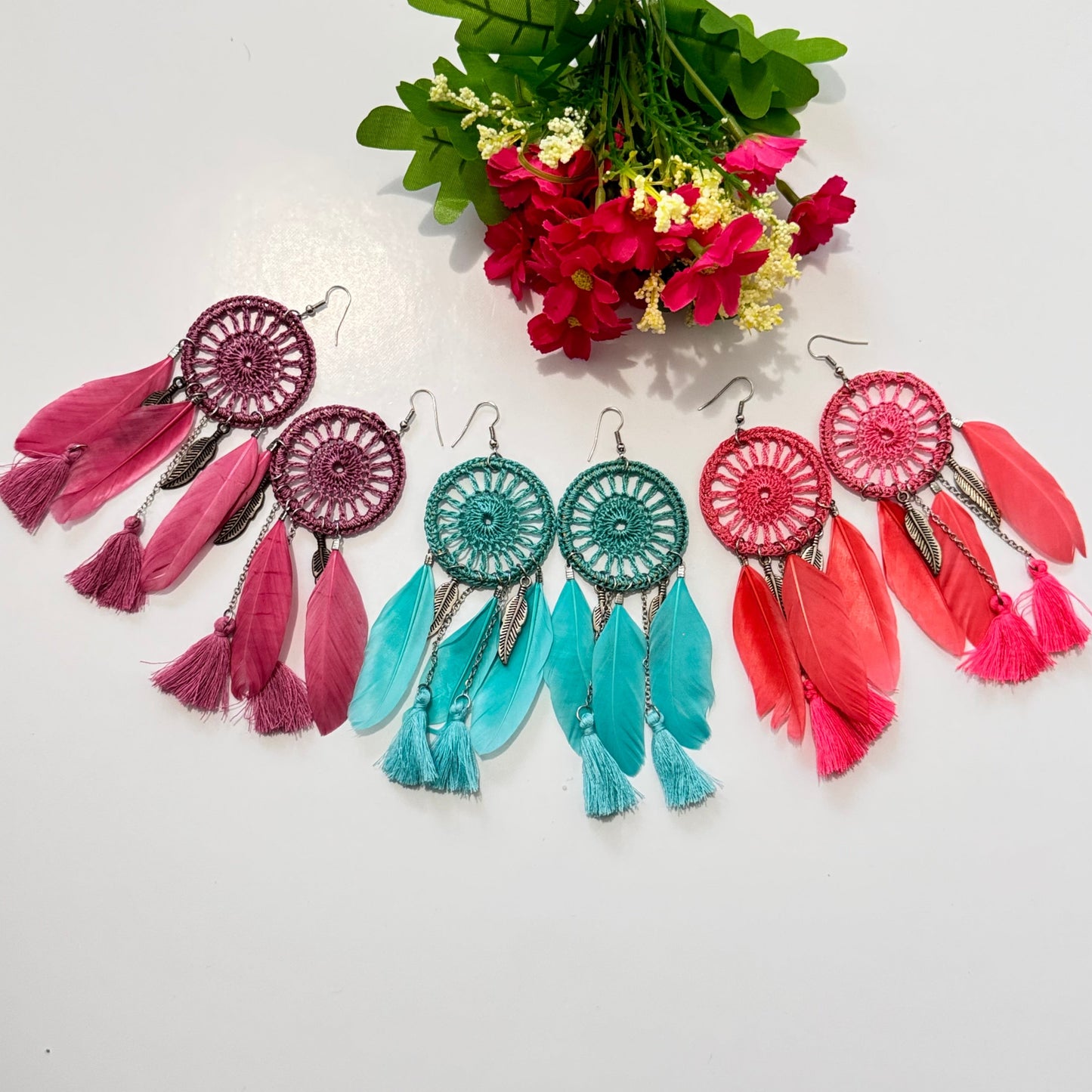 These intricately woven dreamcatcher-inspired earrings feature a stunning circular lace design, adorned with delicate feathers, silky tassels, and metallic leaf charms that sway beautifully with every movement.