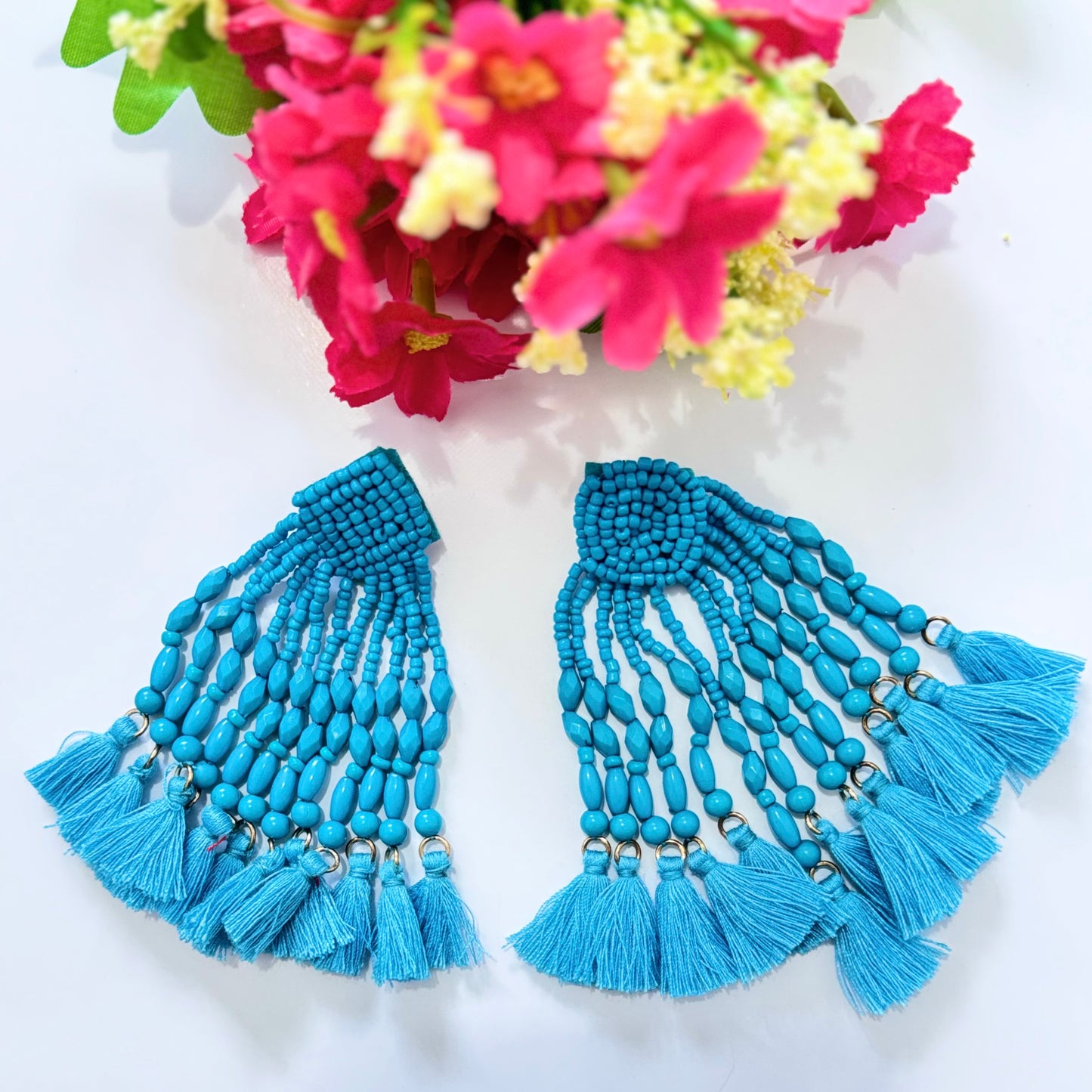 Crafted with intricate seed bead detailing and cascading strands of smooth, polished beads, these earrings exude a bold, eye-catching charm. The vibrant hues of turquoise and fiery red add a striking pop of color to any outfit, making them the perfect accessory for special occasions, beach vacations, or everyday glamour.