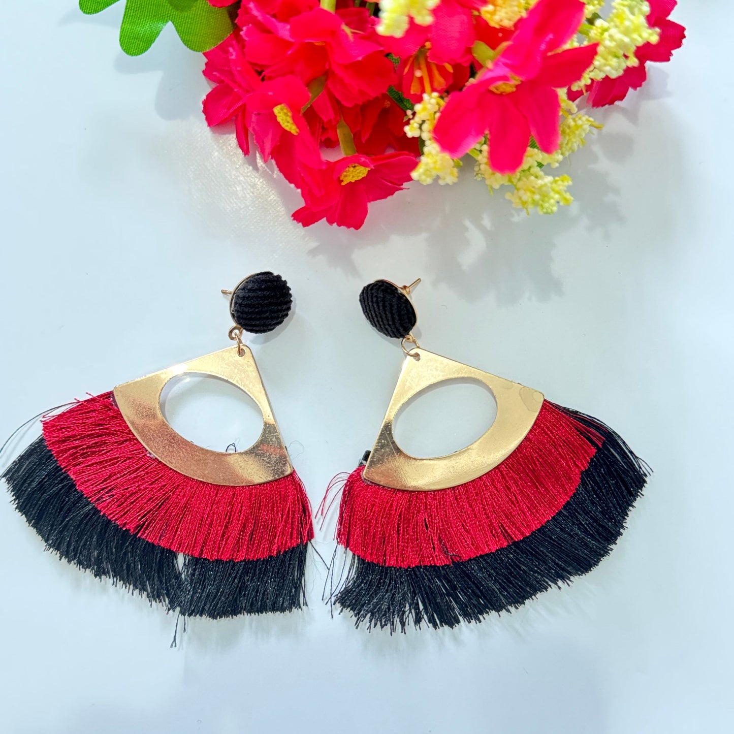 Featuring a sleek gold-tone geometric frame, these eye-catching accessories are adorned with a stunning fringe in striking red and black, adding a dramatic flair to any look. The lightweight, flowy tassels create a mesmerizing movement, making them the perfect standout piece for special occasions or everyday glam.