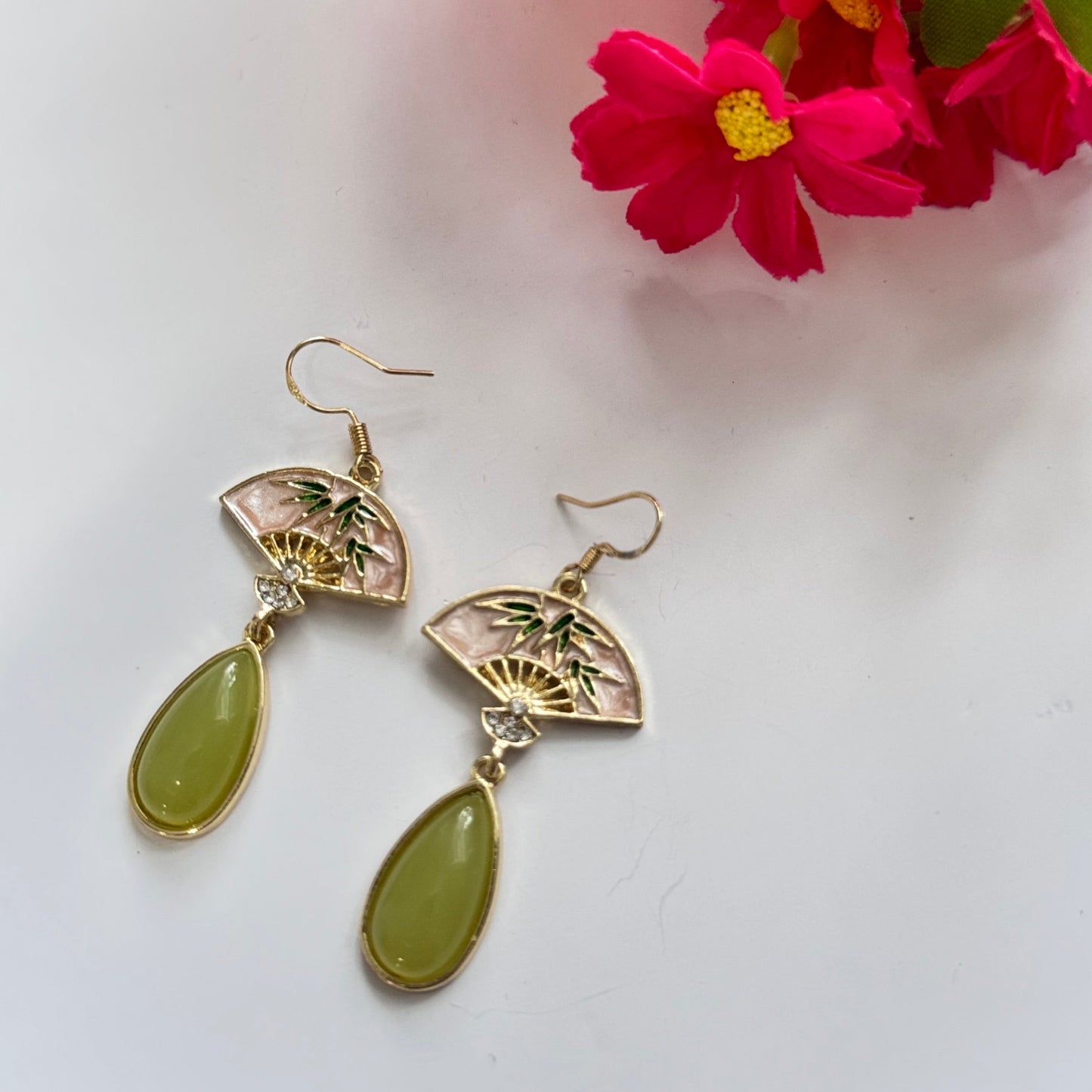 Step into a world of sophisticated charm with these exquisite Oriental Fan Drop Earrings, blending cultural elegance with modern allure. Featuring a delicate gold-toned fan motif, adorned with bamboo details and sparkling crystal accents, these earrings exude grace and refinement.