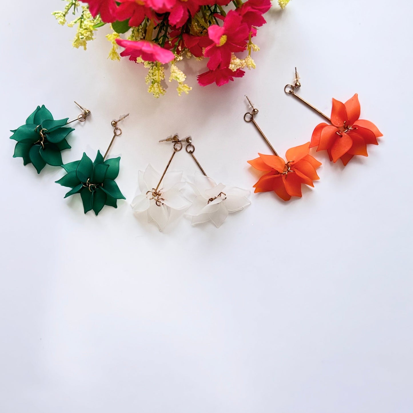 Embrace nature-inspired elegance with these stunning floral drop earrings, designed to add a fresh and feminine touch to any outfit. Featuring delicate, layered petals in rich emerald green, classic white, and vibrant orange, these statement pieces exude charm and sophistication. Suspended from sleek gold-tone accents, they offer a perfect balance of bold color and lightweight comfort.