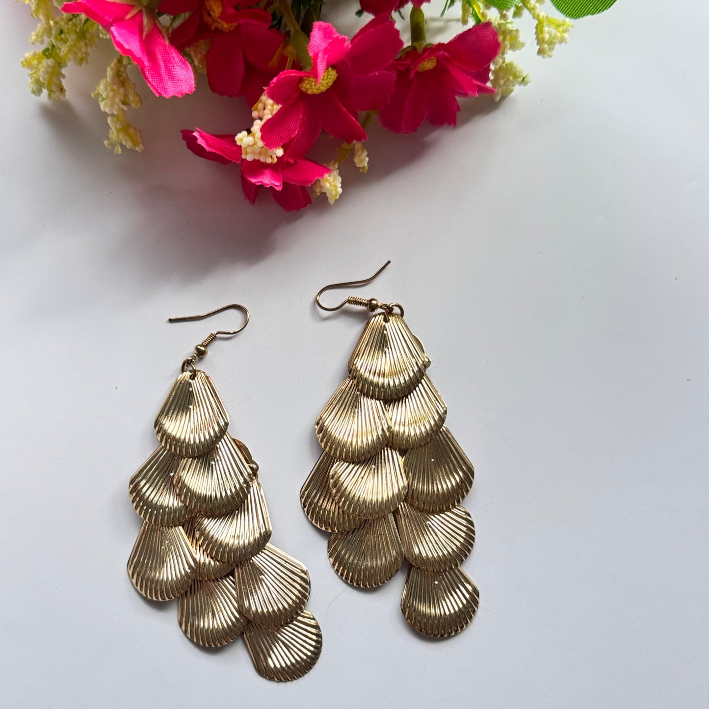 Introducing our Golden Cascade Shell Earrings, a stunning statement piece inspired by the elegance of ocean waves and timeless luxury. Designed with multiple layers of delicately textured, fan-shaped golden charms, these earrings create a mesmerizing waterfall effect that catches the light with every movement.