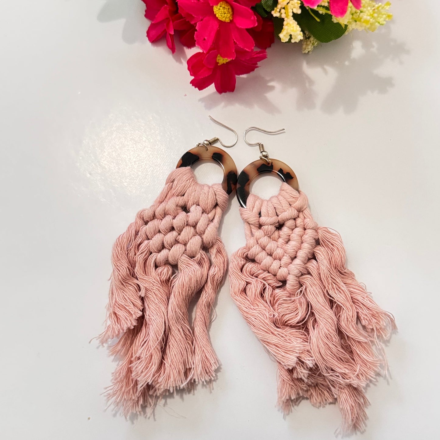 These stunning earrings showcase intricate macramé knotting in soft, natural cream and blush pink hues, complemented by a chic tortoiseshell ring that adds a touch of sophistication. The lightweight, flowy tassels create movement and charm, making these earrings the ultimate statement accessory for any outfit.