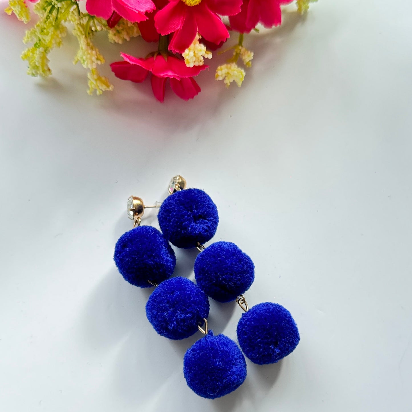 Designed to make a bold statement, these playful yet chic earrings feature three fluffy, lightweight pom-poms stacked elegantly for a dynamic, eye-catching effect. Available in fiery orange, deep royal blue, and radiant sunshine yellow, these earrings bring a fun and energetic touch to any outfit.
