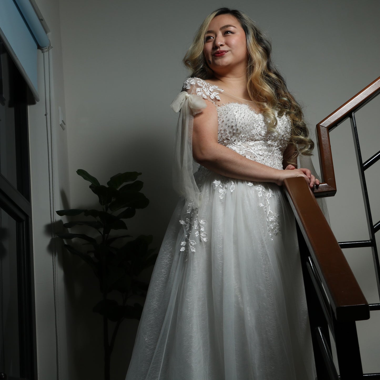 This is a light, ethereal wedding dress featuring delicate floral embroidery and beadwork. The gown has an off-the-shoulder design with sheer tulle straps tied into bows, adding a romantic touch. The bodice is adorned with intricate pearl and lace detailing, while the flowing tulle skirt is embellished with embroidered leaves, creating an elegant and whimsical look.