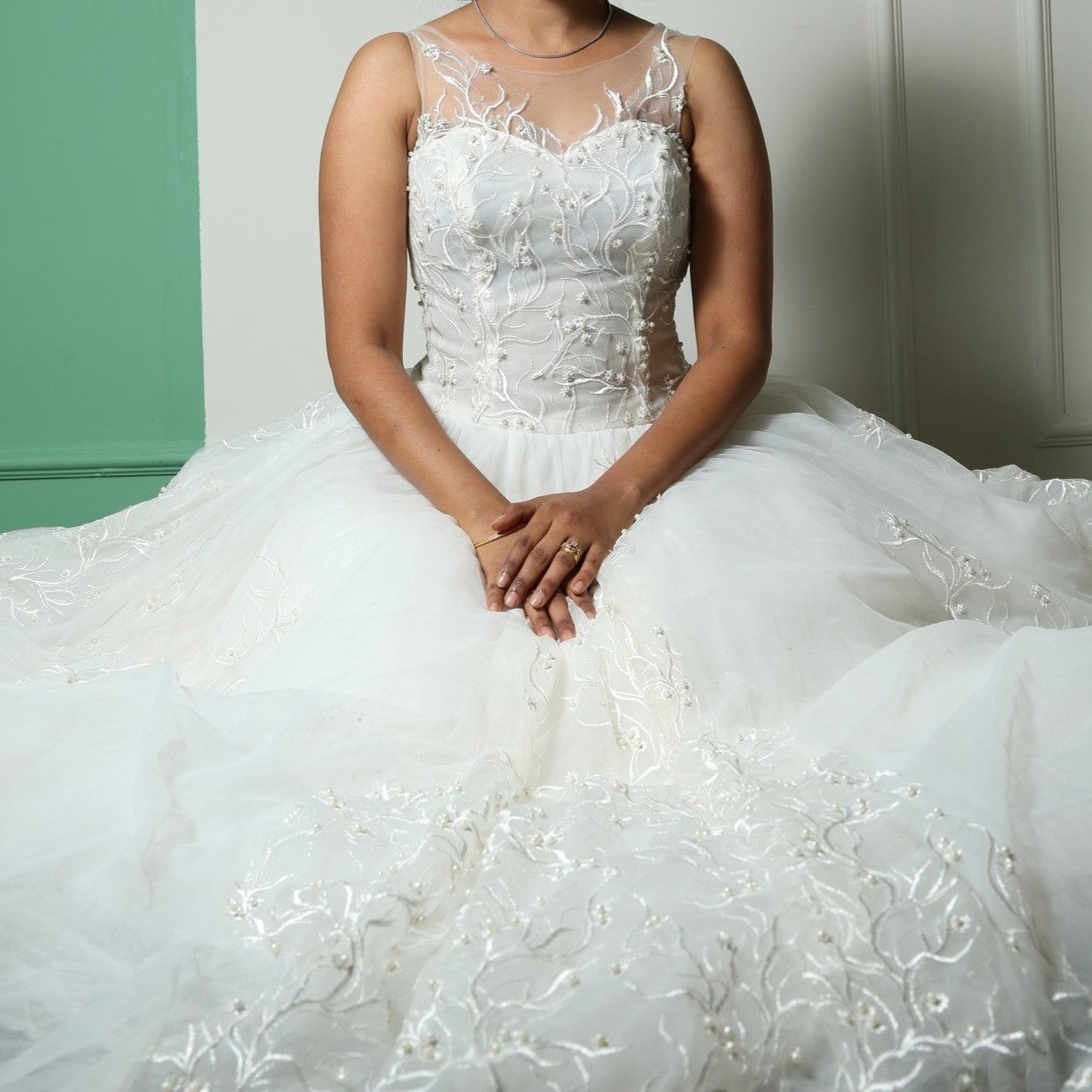 This wedding gown is a light and airy gown featuring a sheer illusion neckline and intricate floral embroidery on the bodice. The flowing tulle skirt is delicately adorned with subtle embellishments, adding an ethereal touch to its elegant silhouette.