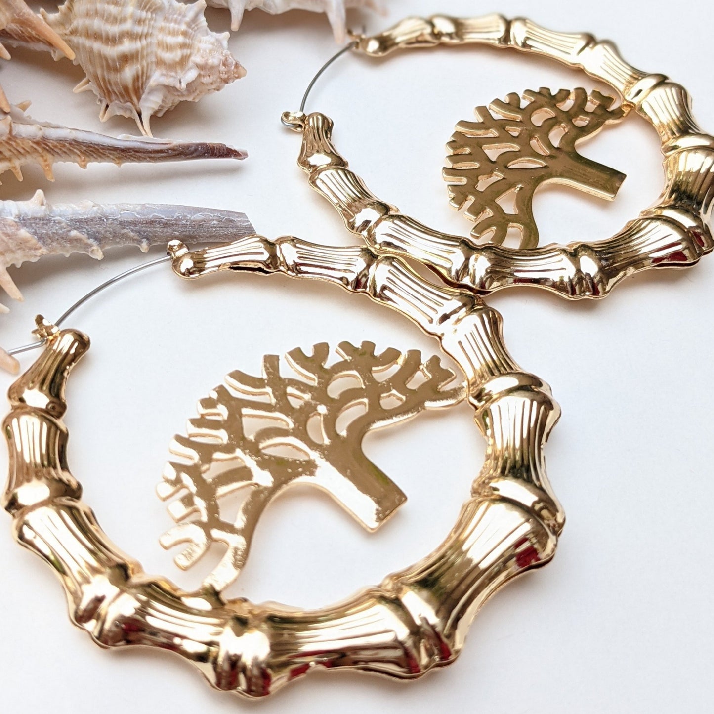 Elevate your style with these stunning gold bamboo hoop earrings, featuring an intricate Tree of Life centerpiece—a timeless symbol of strength, growth, and connection. Crafted with exquisite detail, these bold statement earrings boast a radiant high-polish gold finish, capturing the essence of nature’s beauty while exuding luxury and sophistication. These hoops are the perfect blend of earthy elegance and contemporary fashion, making them a must-have for your collection.
