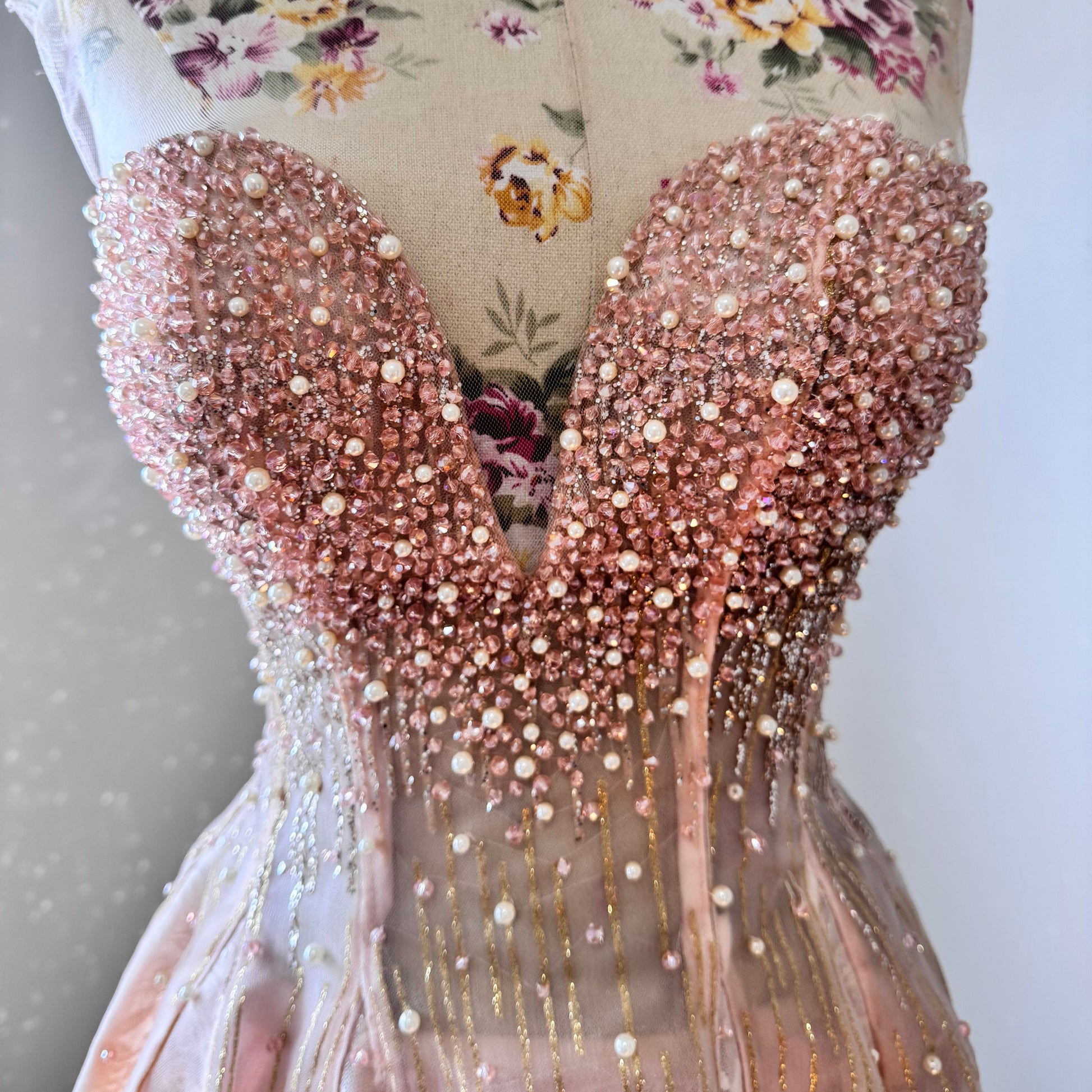 The dress in the image is an elegant, heavily embellished gown with a fitted bodice and a voluminous skirt. It features intricate beadwork and embroidery, giving it a luxurious and opulent look. The sheer illusion neckline adds a delicate touch, while the structured, corset-like bodice enhances the silhouette. The fabric appears to be thick and richly adorned, making the dress quite heavy. The overall design exudes a regal and glamorous feel, perfect for a formal event or gala.