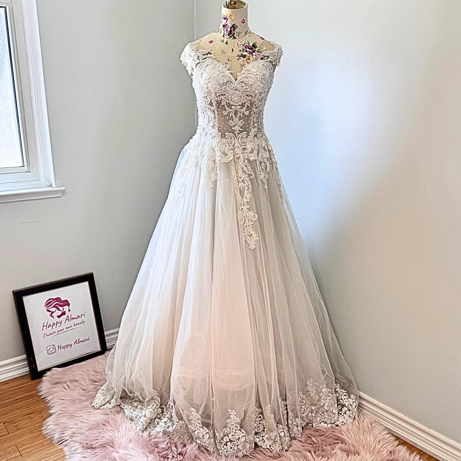 Ethereal elegance meets timeless romance in this breathtaking bridal gown, designed to make you feel like an absolute vision on your special day. Featuring an intricately beaded bodice with delicate lace appliqués cascading onto a flowing tulle skirt, this gown embodies grace and sophistication. The illusion off-shoulder neckline and sweetheart design create a captivating silhouette, while the soft, airy layers add a dreamy, fairytale-like effect with every step. 