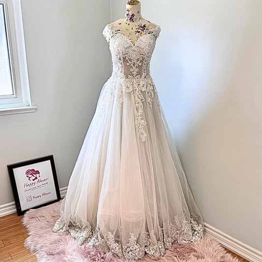 Ethereal elegance meets timeless romance in this breathtaking bridal gown, designed to make you feel like an absolute vision on your special day. Featuring an intricately beaded bodice with delicate lace appliqués cascading onto a flowing tulle skirt, this gown embodies grace and sophistication. The illusion off-shoulder neckline and sweetheart design create a captivating silhouette, while the soft, airy layers add a dreamy, fairytale-like effect with every step. 