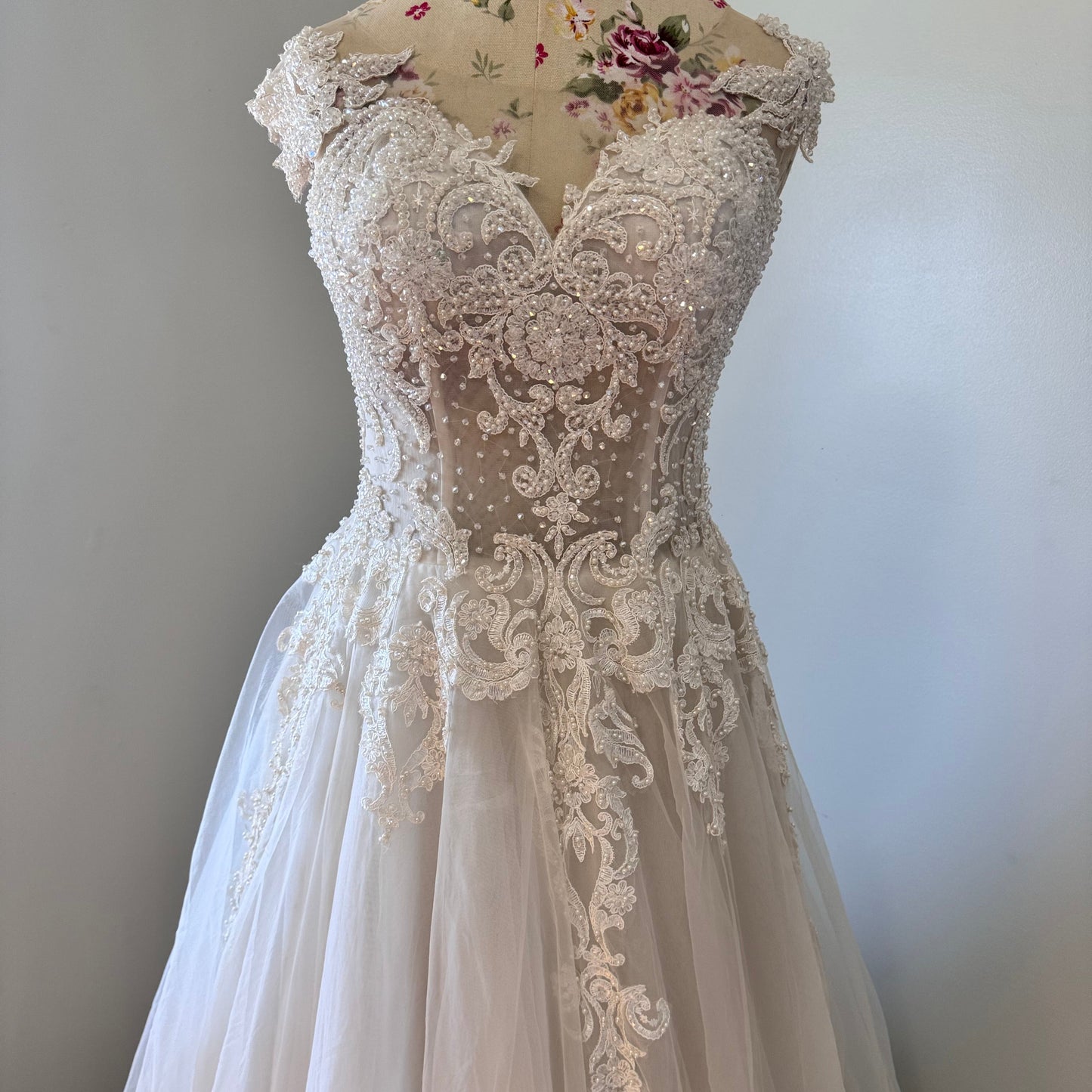 Ethereal elegance meets timeless romance in this breathtaking bridal gown, designed to make you feel like an absolute vision on your special day. Featuring an intricately beaded bodice with delicate lace appliqués cascading onto a flowing tulle skirt, this gown embodies grace and sophistication. The illusion off-shoulder neckline and sweetheart design create a captivating silhouette, while the soft, airy layers add a dreamy, fairytale-like effect with every step. 