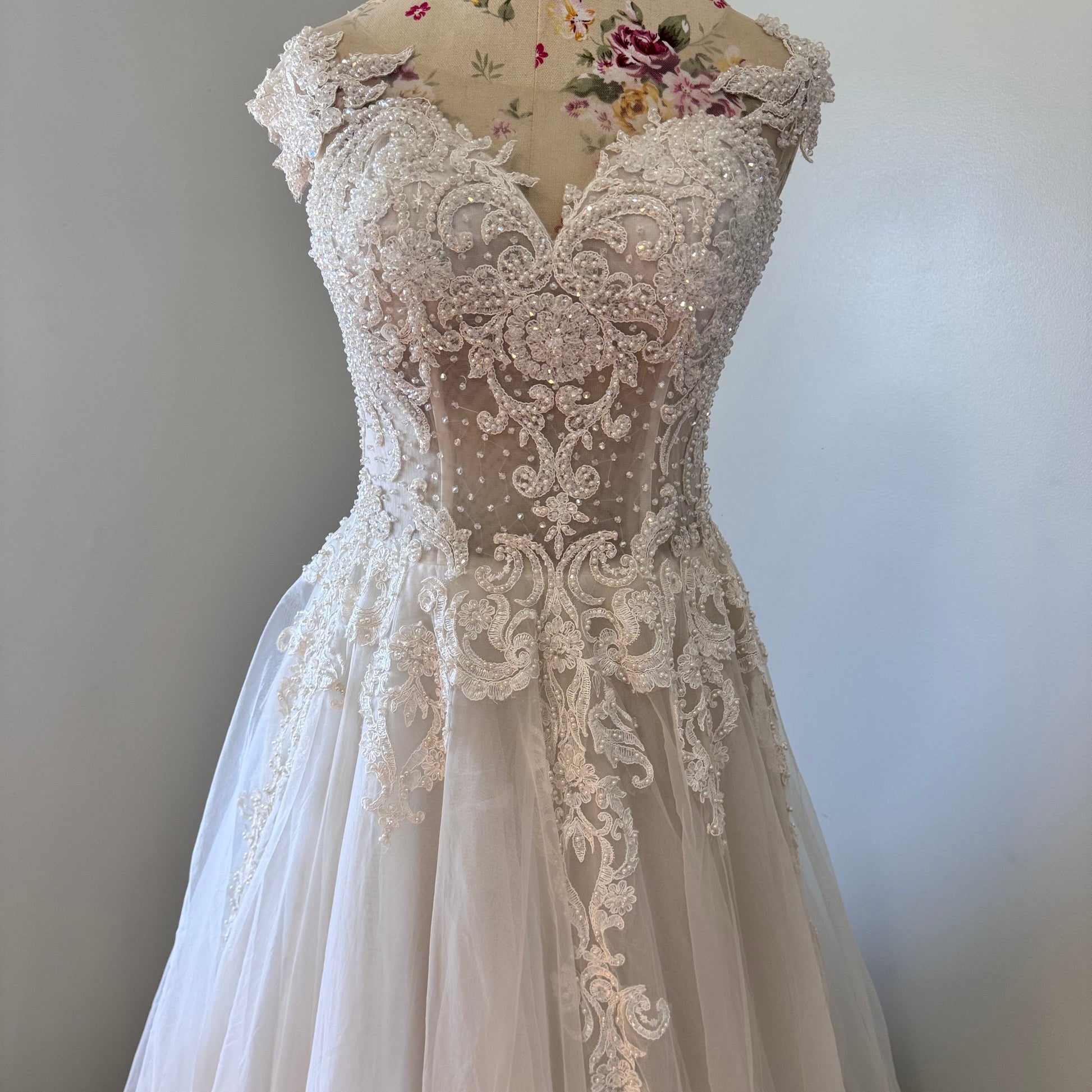 Ethereal elegance meets timeless romance in this breathtaking bridal gown, designed to make you feel like an absolute vision on your special day. Featuring an intricately beaded bodice with delicate lace appliqués cascading onto a flowing tulle skirt, this gown embodies grace and sophistication. The illusion off-shoulder neckline and sweetheart design create a captivating silhouette, while the soft, airy layers add a dreamy, fairytale-like effect with every step. 