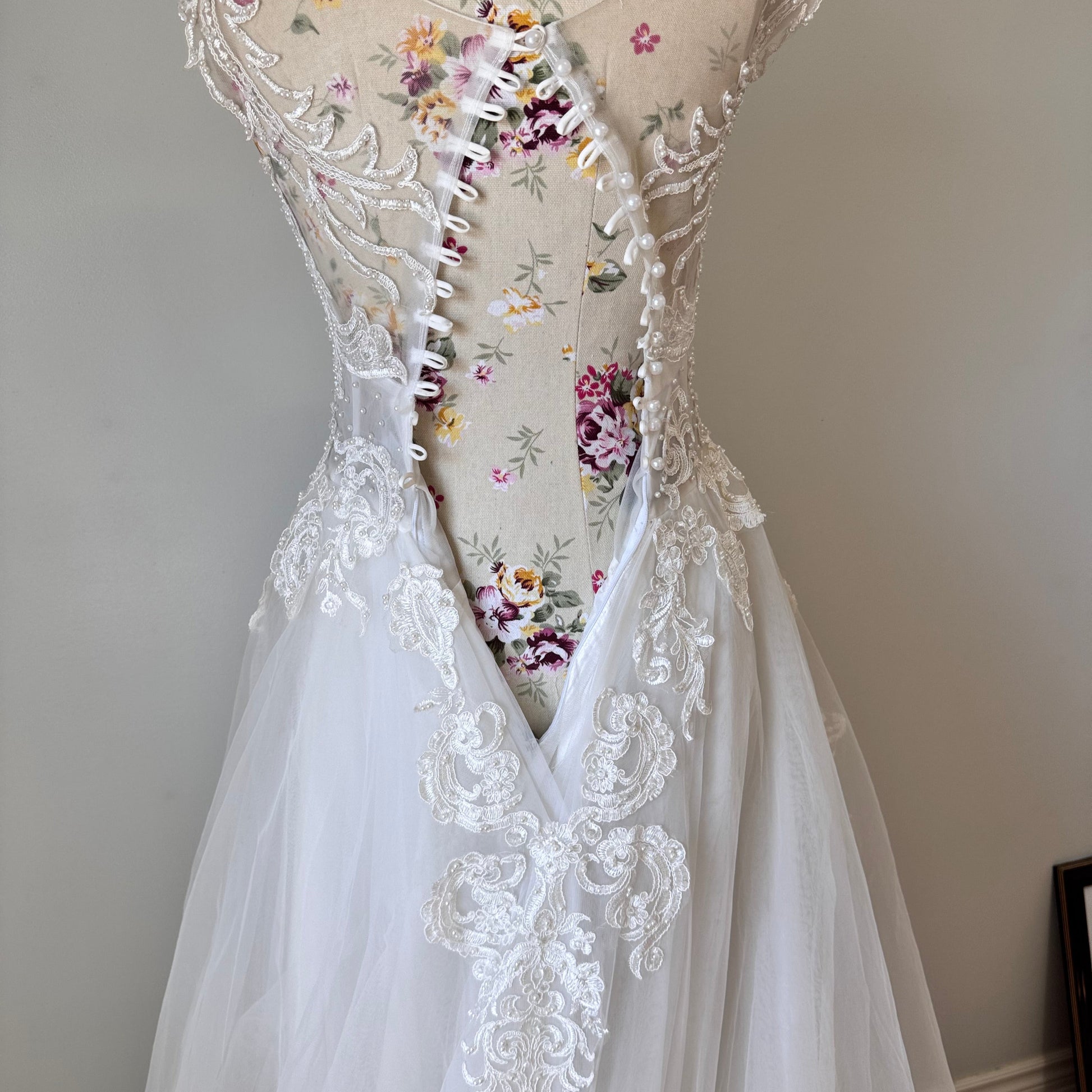 Ethereal elegance meets timeless romance in this breathtaking bridal gown, designed to make you feel like an absolute vision on your special day. Featuring an intricately beaded bodice with delicate lace appliqués cascading onto a flowing tulle skirt, this gown embodies grace and sophistication. The illusion off-shoulder neckline and sweetheart design create a captivating silhouette, while the soft, airy layers add a dreamy, fairytale-like effect with every step. 