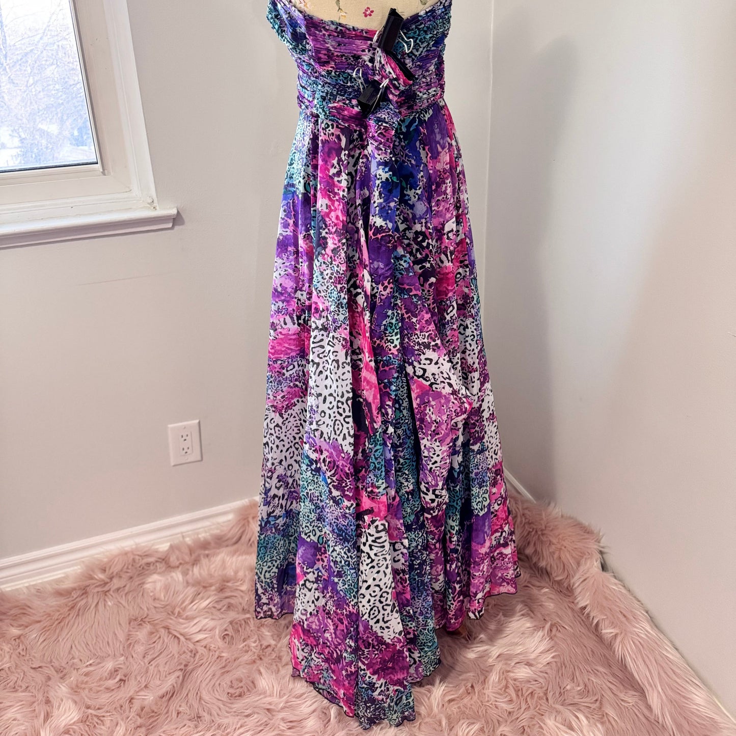Unleash your bold, vibrant spirit with this breathtaking strapless gown, a mesmerizing fusion of art and fashion. Designed to turn heads, this flowing masterpiece features an explosion of rich purples, electric blues, and striking pinks in a captivating abstract animal print. The ruched bodice flatters the silhouette, while the voluminous skirt cascades effortlessly, creating a dreamy, ethereal effect with every step. 