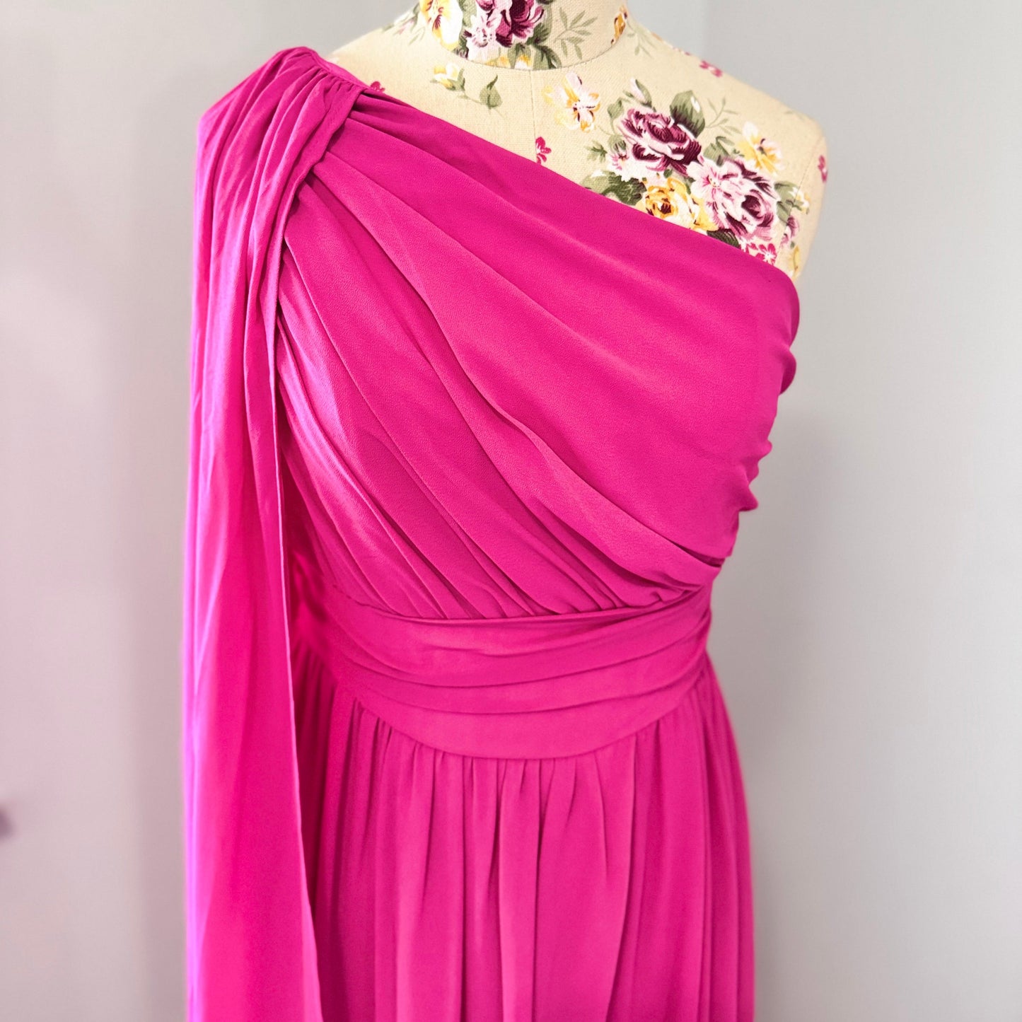 Step into effortless elegance with this breathtaking fuchsia one-shoulder gown, designed to make a statement at any event. Featuring a gracefully draped sleeve that cascades like a flowing waterfall, this dress exudes confidence, sophistication, and timeless charm. The cinched waist enhances your silhouette, while the soft, flowing fabric moves beautifully with every step.