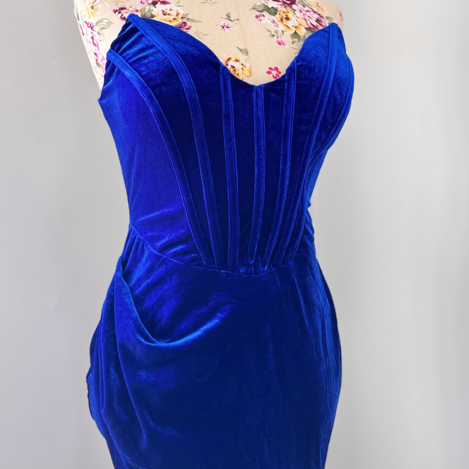 Step into timeless elegance with this breathtaking previously cherished royal blue velvet evening gown, designed to turn heads at any event. Crafted from rich, ultra-soft velvet, this figure-hugging masterpiece features a structured corset bodice with delicate pleated detailing that accentuates your silhouette. The sweetheart neckline adds a touch of romance, while the flowing skirt with a sultry thigh-high slit creates the perfect balance of sophistication and allure. In perfect condition.