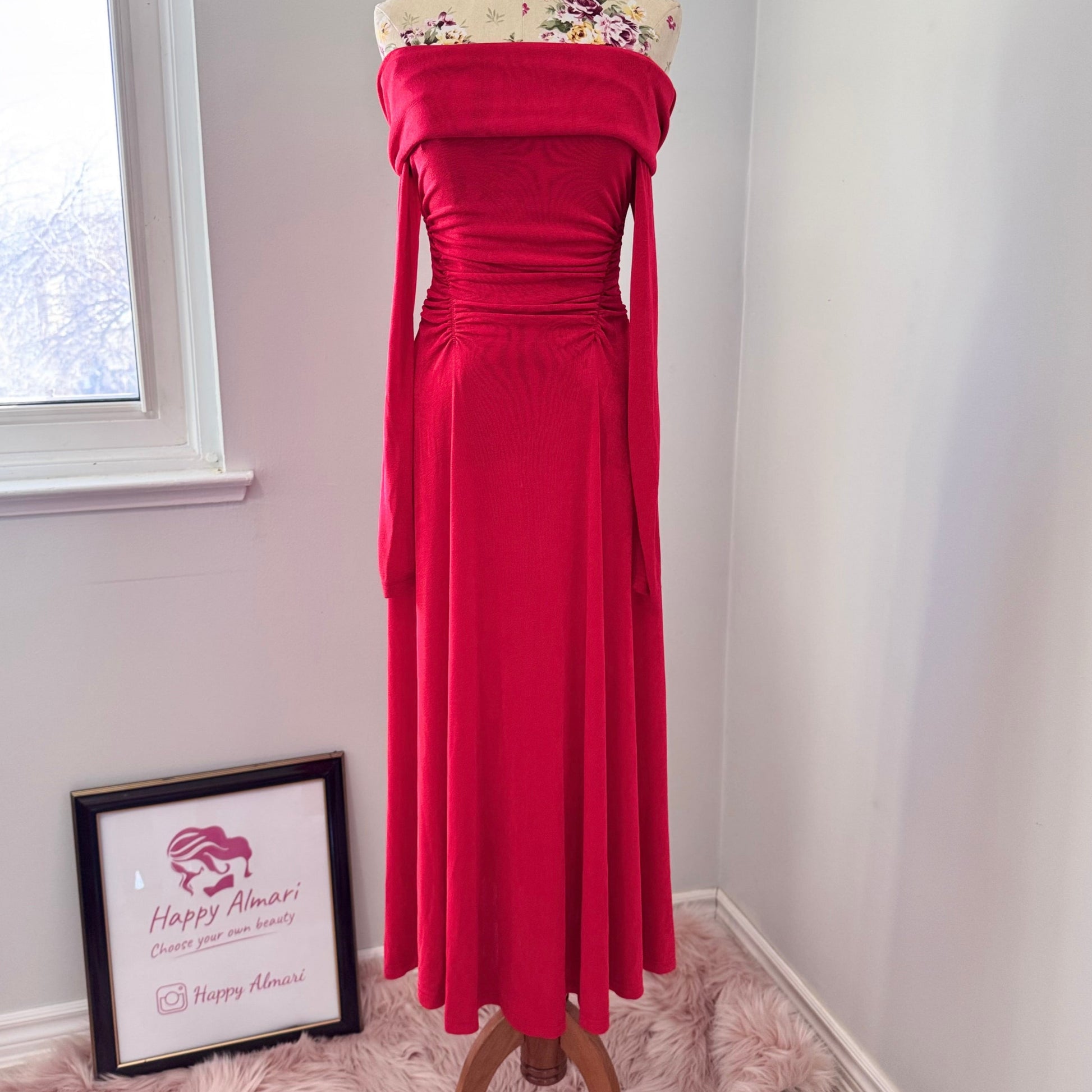 Introducing an exquisite statement piece: this stunning red off-the-shoulder gown is designed to turn heads with its timeless elegance and undeniable allure. Crafted from a soft, draping fabric that hugs your curves in all the right places, this dress features delicate ruched detailing at the waist, creating a flattering silhouette that enhances your natural beauty. The long, flowing sleeves add a touch of drama, while the fold-over neckline brings an effortlessly chic vibe.