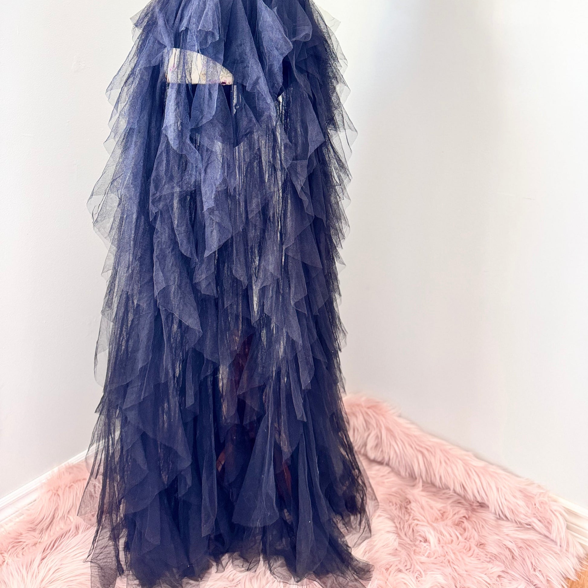 Introducing an black tulle gown that exudes timeless sophistication and drama. Featuring a structured, deep V-cut bodice that enhances the silhouette, this piece is designed with a sleek bodysuit bottom for a flawless, sculpted fit. The fitted waistline flows into cascading layers of soft, ruffled tulle, creating a breathtaking, ethereal effect with every step. This beautifully rehomed gown carries a story of style and elegance, ready to be cherished by its next wearer.
