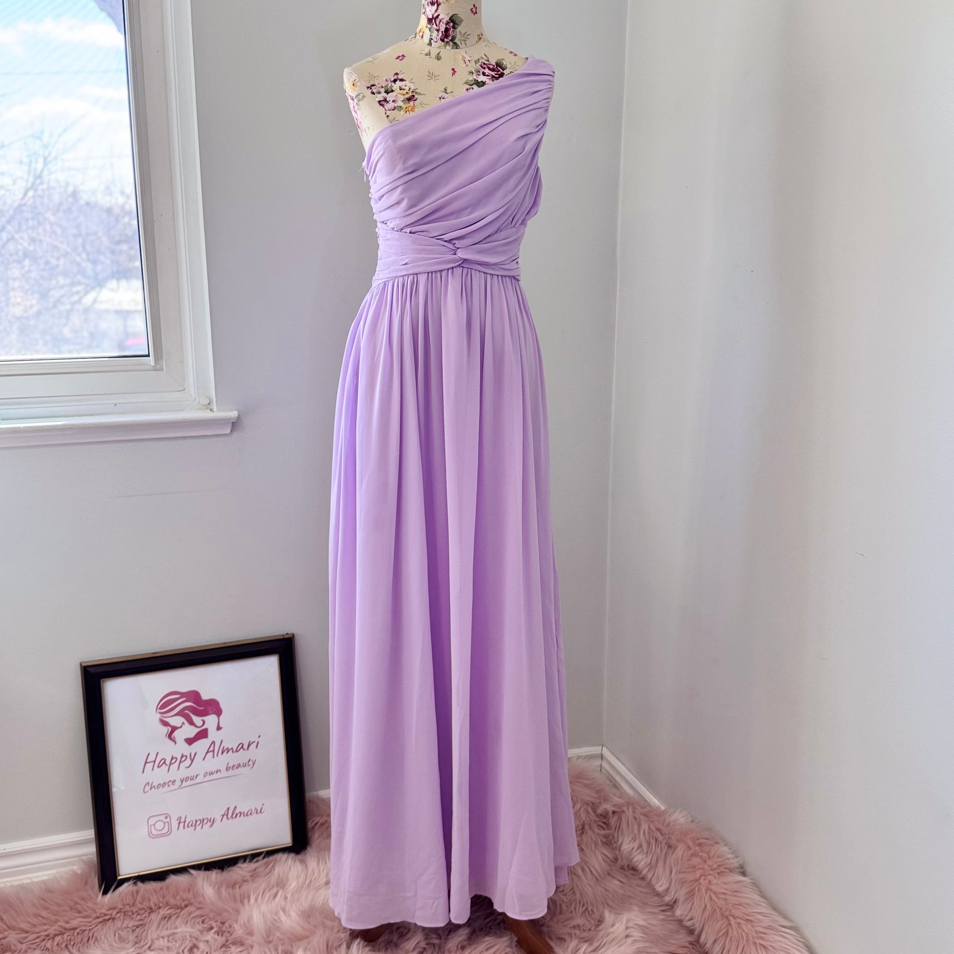 Turn heads in this breathtaking one-shoulder lavender gown, designed to make a statement at weddings, proms, and special occasions. Crafted with delicate pleated draping, a cinched waist for a flattering silhouette, and an elegant flowing skirt, this dress exudes timeless charm. Its soft, ethereal chiffon fabric creates a dreamy and romantic look.