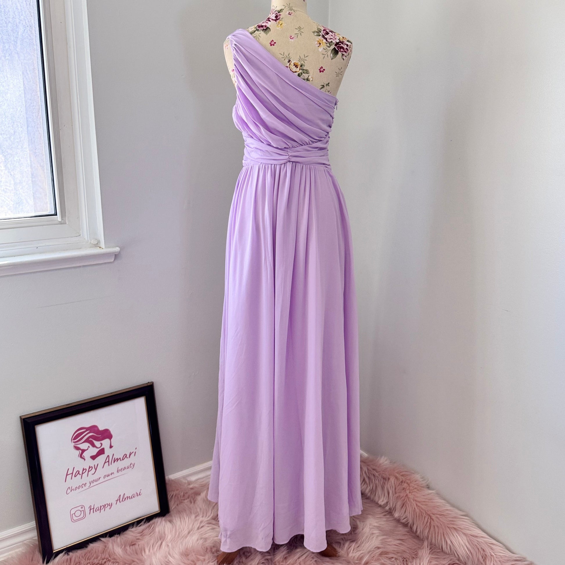Turn heads in this breathtaking one-shoulder lavender gown, designed to make a statement at weddings, proms, and special occasions. Crafted with delicate pleated draping, a cinched waist for a flattering silhouette, and an elegant flowing skirt, this dress exudes timeless charm. Its soft, ethereal chiffon fabric creates a dreamy and romantic look.