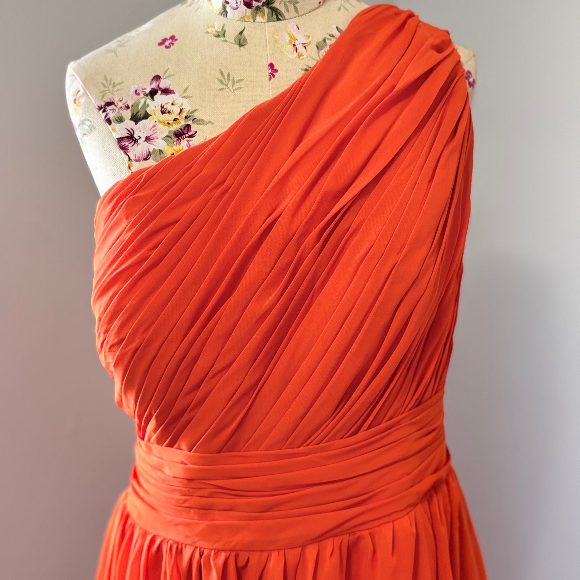 Turn heads with this stunning one-shoulder asymmetrical gown in a bold, fiery orange hue! Designed to make a statement, this dress features intricate pleating across the bodice for a flattering fit, a cinched waist that accentuates your curves, and a flowing high-low skirt that moves beautifully with every step.