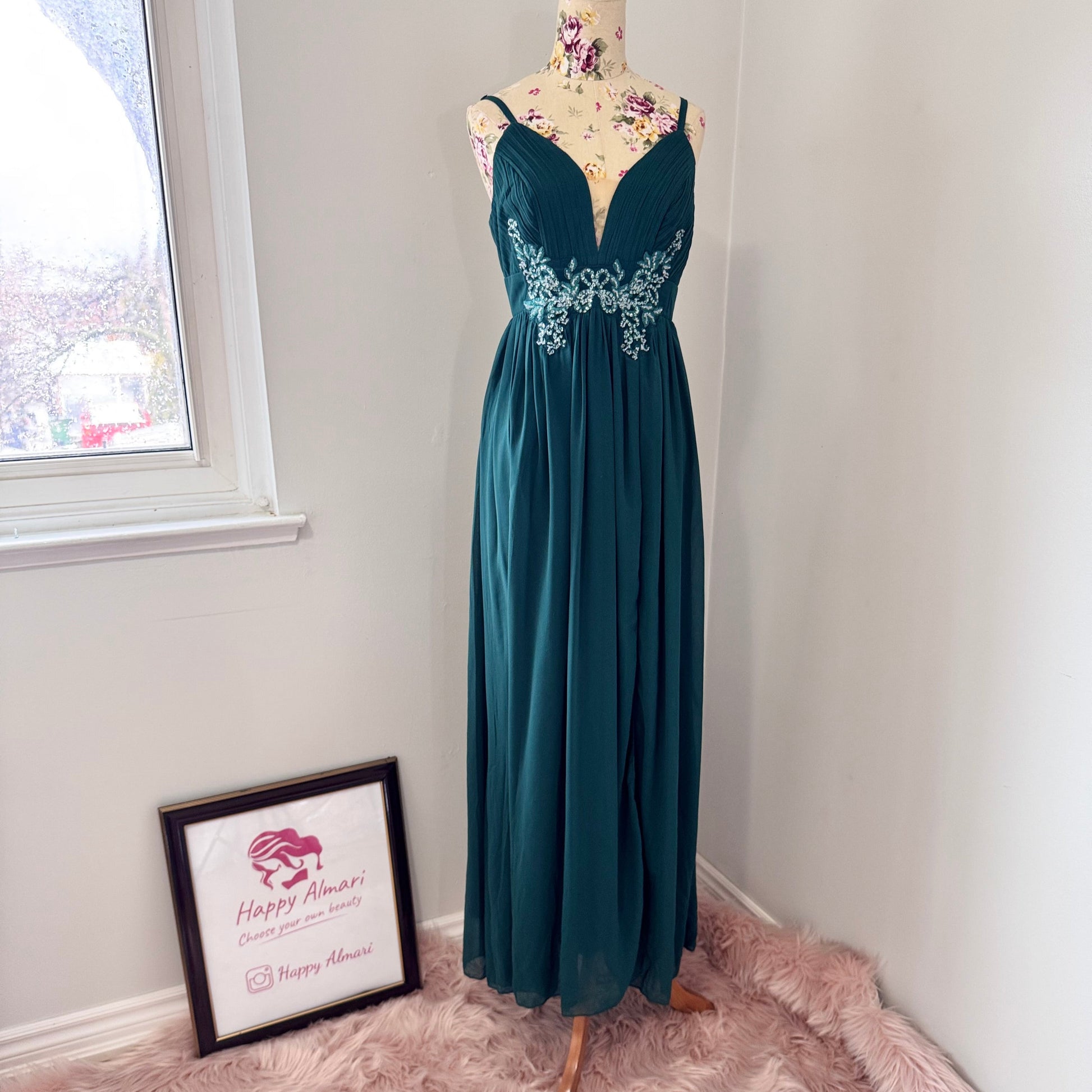Elevate your evening look with this breathtaking emerald green gown, designed to make a statement at any formal occasion. Featuring a figure-flattering silhouette with a pleated bodice, delicate spaghetti straps, and a plunging neckline, this dress exudes effortless elegance. The intricate floral embellishments at the waist add a touch of romance, while the flowing chiffon skirt ensures graceful movement with every step.