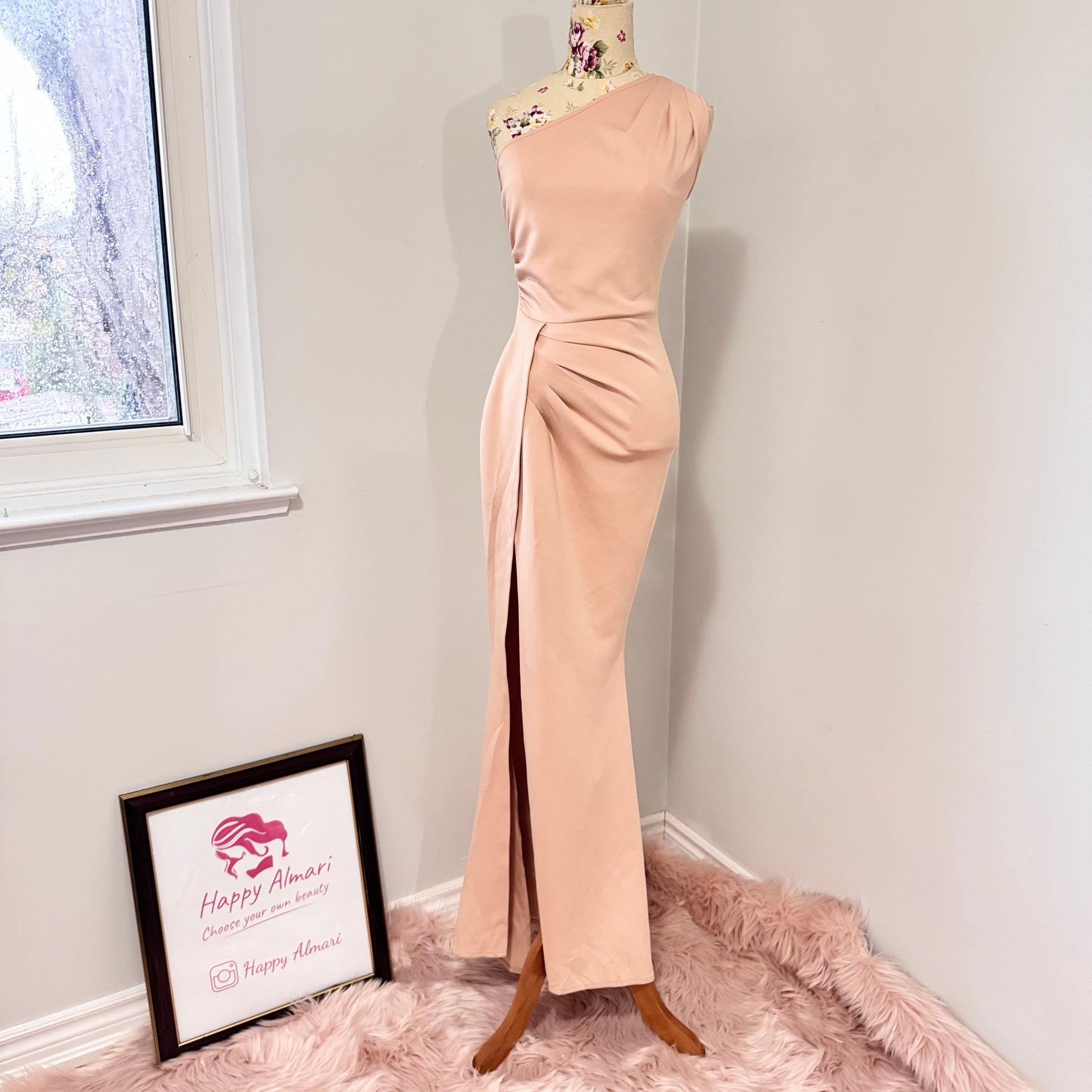 Make an unforgettable entrance in this stunning one-shoulder gown, designed to accentuate your curves with effortless grace. Featuring a sleek asymmetrical neckline and elegantly draped side ruching, this dress flatters from every angle. The high-slit detail adds just the right touch of allure, making it the perfect choice for weddings, formal events, or any special occasion where you want to shine. The soft blush hue complements a variety of skin tones, ensuring a timeless and sophisticated look. 