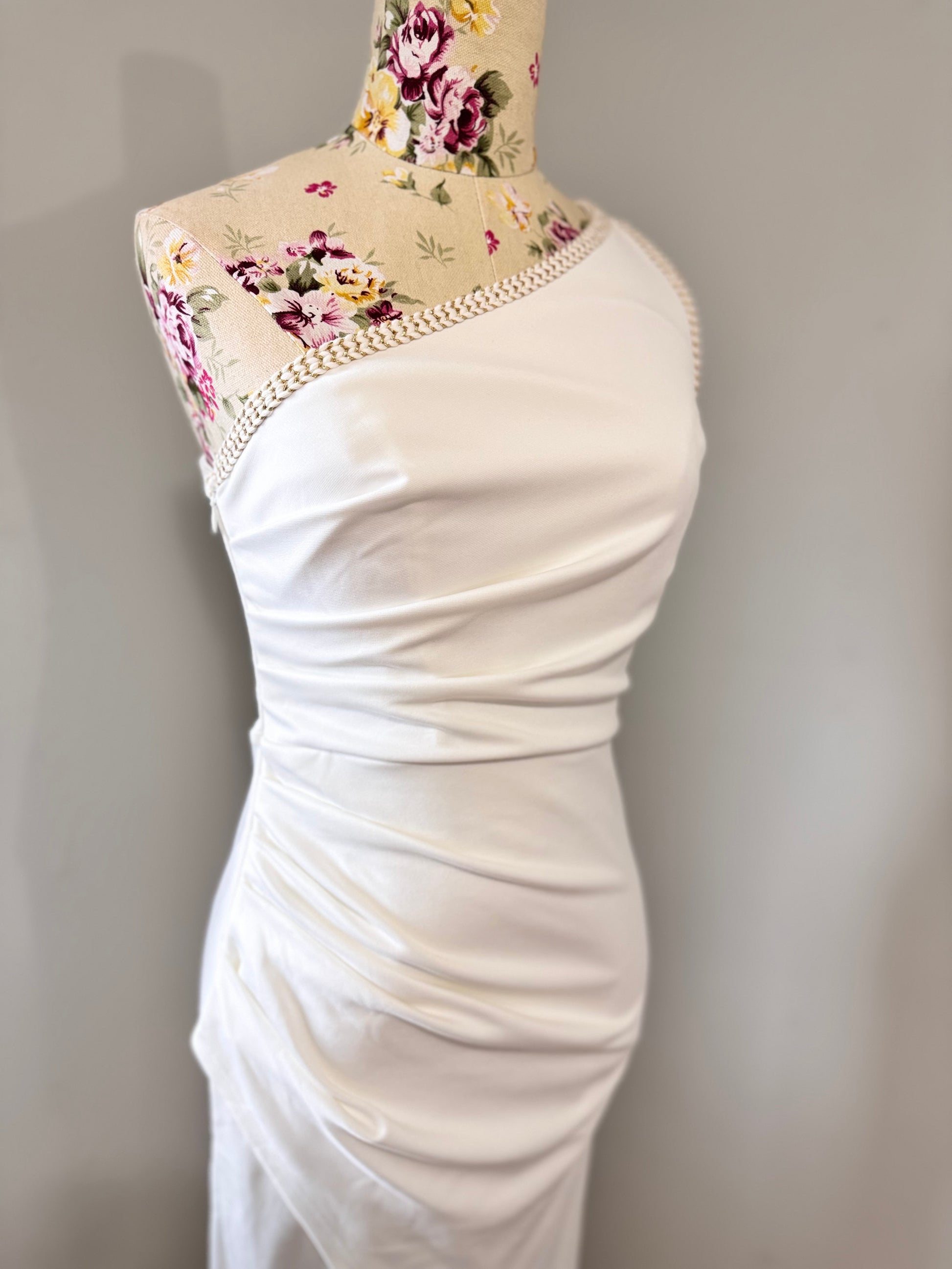 Elevate your style with this stunning white one-shoulder midi dress, designed to make a statement at any event. Featuring an asymmetrical neckline with elegant pearl-like trim, a flattering ruched waist, and a sultry front slit, this dress exudes sophistication and charm. Crafted from high-quality fabric, it drapes beautifully to accentuate your silhouette. 