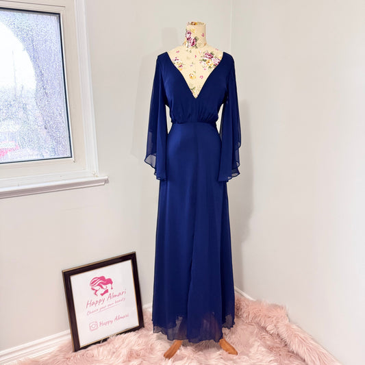 Turn heads in this stunning deep navy gown that radiates elegance and grace. Designed with a flowy chiffon overlay, a flattering cinched waist, and dreamy flutter sleeves, this dress is perfect for formal events, weddings, or special occasions. The deep V-neckline and subtle front slit add just the right touch of sophistication and allure. This gently cherished piece is in excellent condition, ready for a new owner to make unforgettable memories.