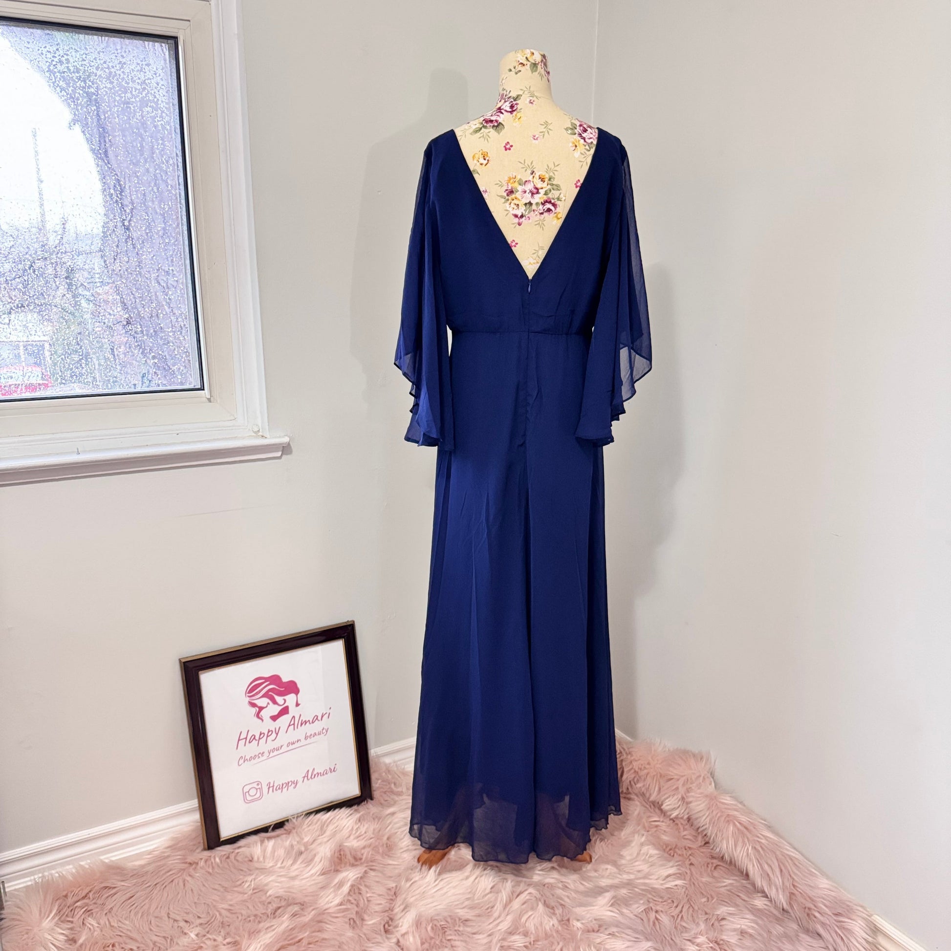 Turn heads in this stunning deep navy gown that radiates elegance and grace. Designed with a flowy chiffon overlay, a flattering cinched waist, and dreamy flutter sleeves, this dress is perfect for formal events, weddings, or special occasions. The deep V-neckline and subtle front slit add just the right touch of sophistication and allure. This gently cherished piece is in excellent condition, ready for a new owner to make unforgettable memories.