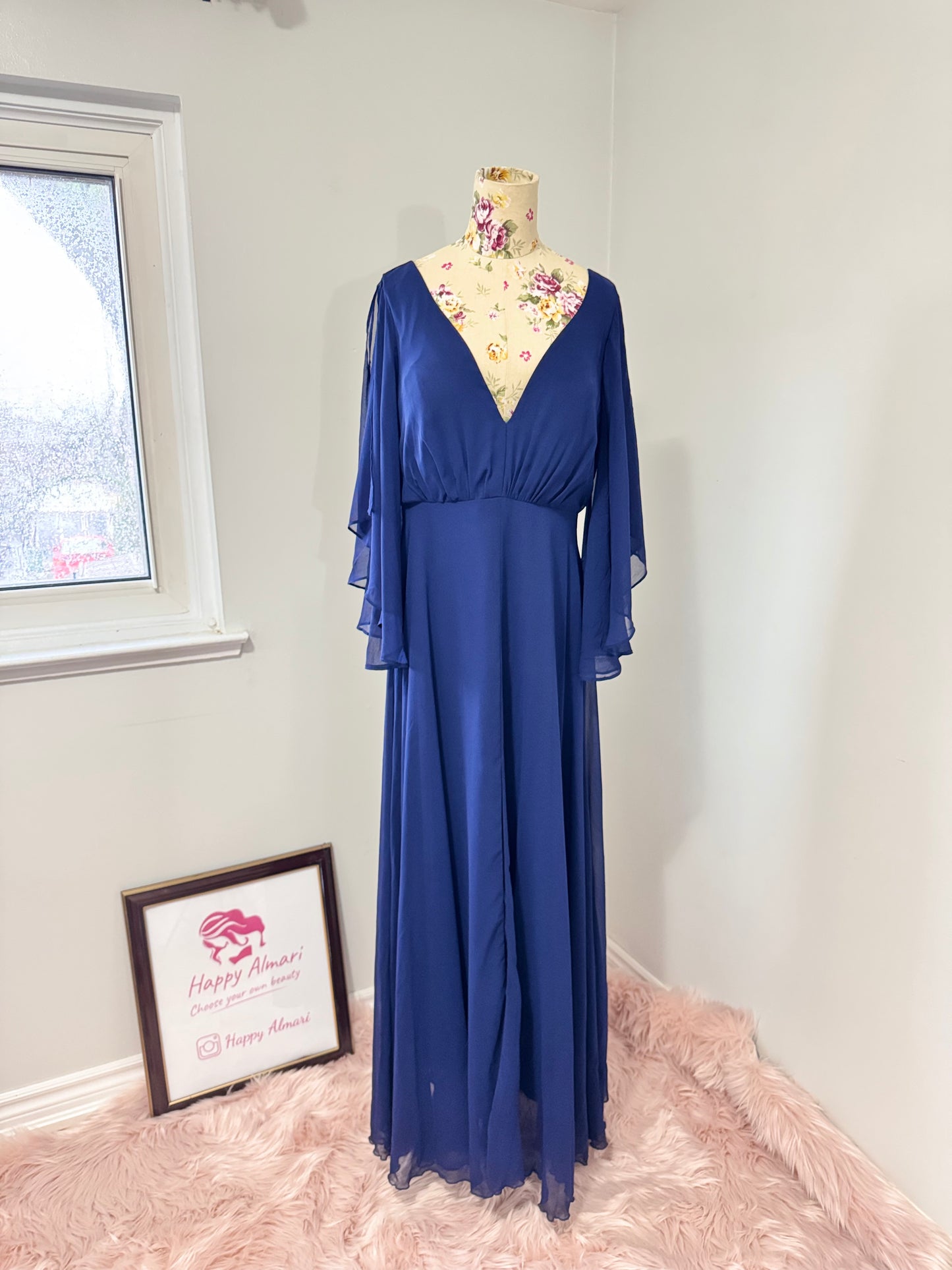 Turn heads in this stunning deep navy gown that radiates elegance and grace. Designed with a flowy chiffon overlay, a flattering cinched waist, and dreamy flutter sleeves, this dress is perfect for formal events, weddings, or special occasions. The deep V-neckline and subtle front slit add just the right touch of sophistication and allure. This gently cherished piece is in excellent condition, ready for a new owner to make unforgettable memories.