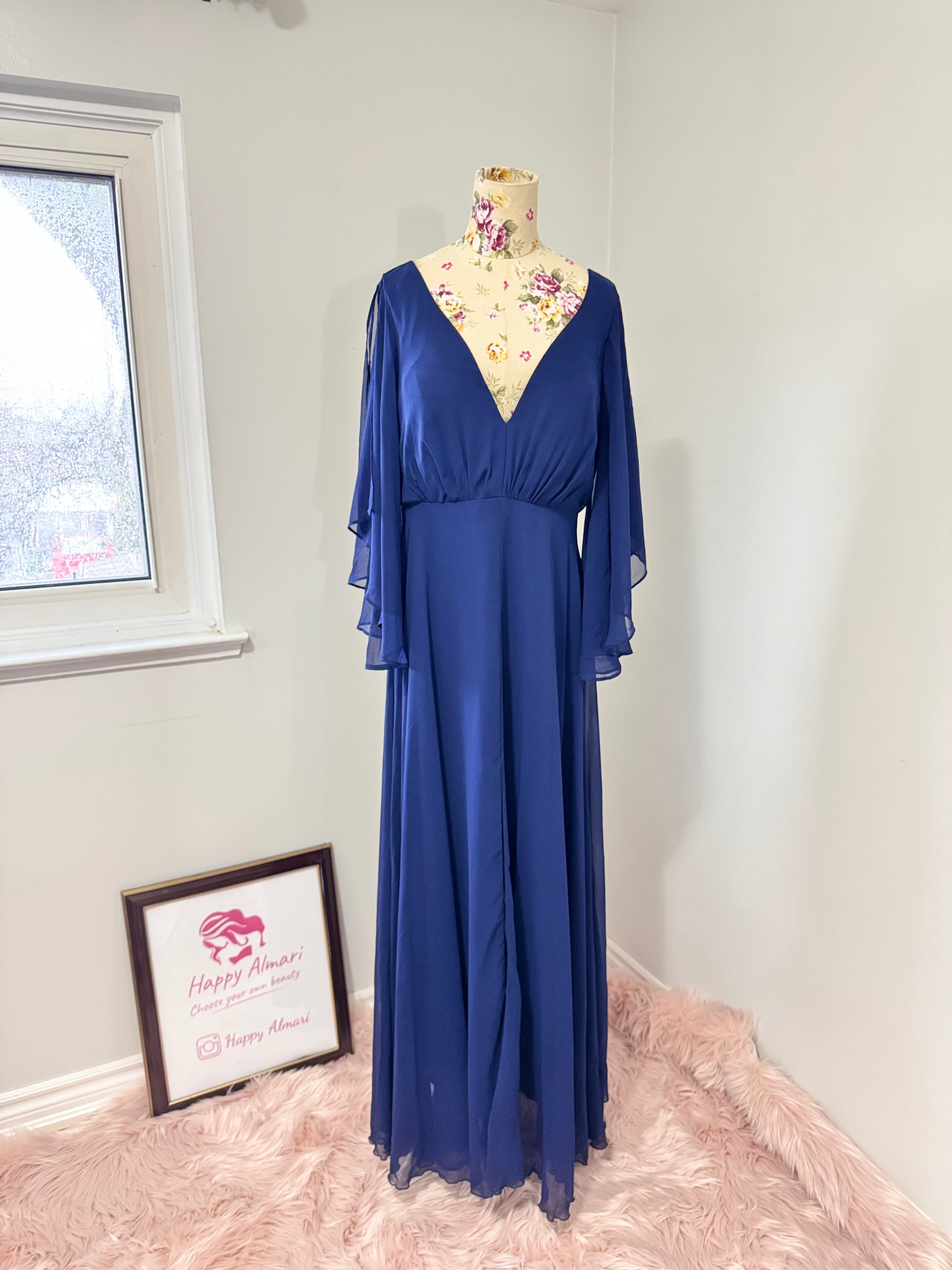 Turn heads in this stunning deep navy gown that radiates elegance and grace. Designed with a flowy chiffon overlay, a flattering cinched waist, and dreamy flutter sleeves, this dress is perfect for formal events, weddings, or special occasions. The deep V-neckline and subtle front slit add just the right touch of sophistication and allure. This gently cherished piece is in excellent condition, ready for a new owner to make unforgettable memories.