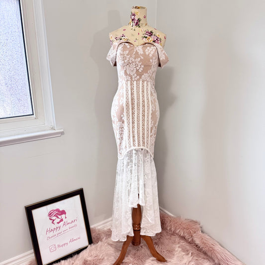 This breathtaking off-shoulder lace gown is designed to captivate with its intricate floral lace detailing and figure-enhancing silhouette. The delicate sheer bodice, complemented by a soft nude underlayer, creates a stunning contrast, while the high-low lace hemline adds a touch of modern romance.