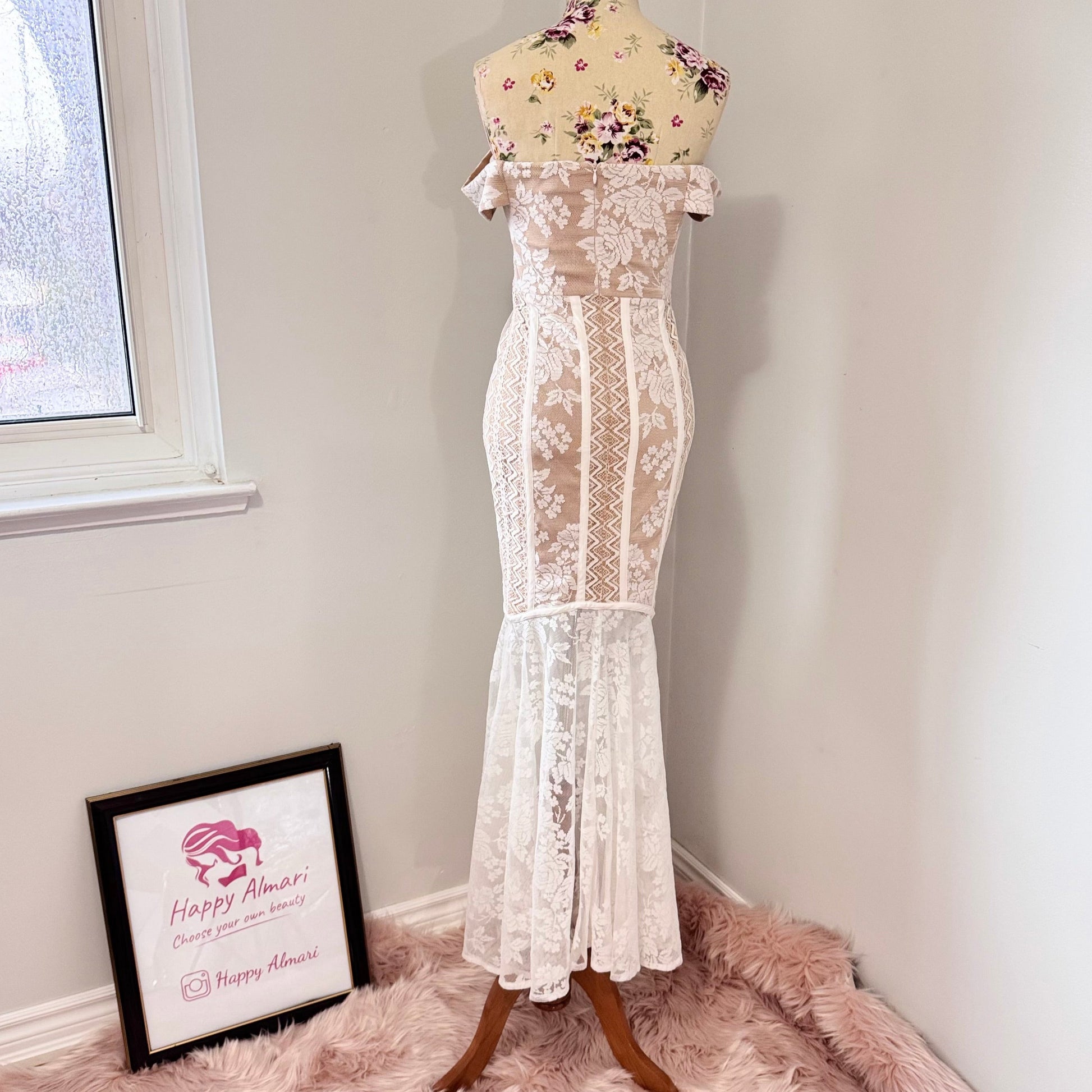 This breathtaking off-shoulder lace gown is designed to captivate with its intricate floral lace detailing and figure-enhancing silhouette. The delicate sheer bodice, complemented by a soft nude underlayer, creates a stunning contrast, while the high-low lace hemline adds a touch of modern romance.