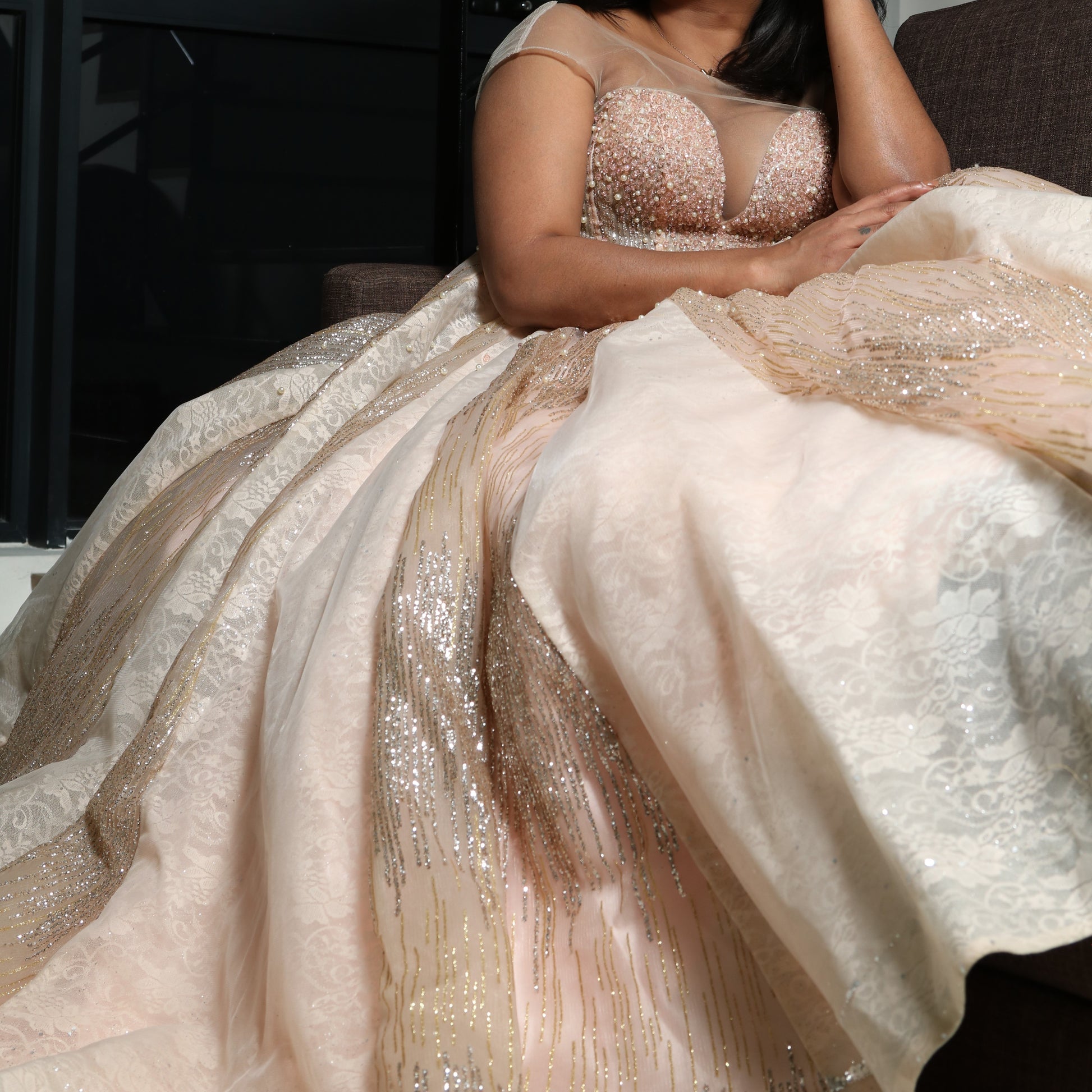 The dress in the image is an elegant, heavily embellished gown with a fitted bodice and a voluminous skirt. It features intricate beadwork and embroidery, giving it a luxurious and opulent look. The sheer illusion neckline adds a delicate touch, while the structured, corset-like bodice enhances the silhouette. The fabric appears to be thick and richly adorned, making the dress quite heavy. The overall design exudes a regal and glamorous feel, perfect for a formal event or gala.