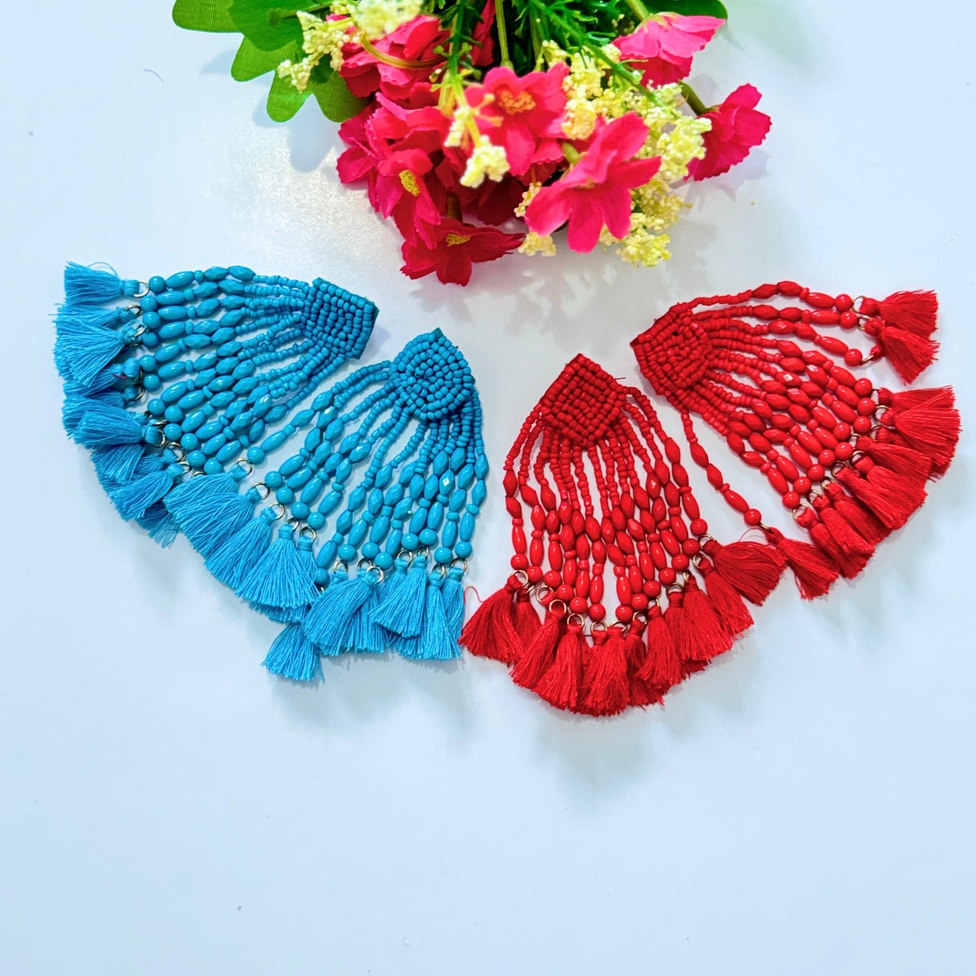  Crafted with intricate seed bead detailing and cascading strands of smooth, polished beads, these earrings exude a bold, eye-catching charm. The vibrant hues of turquoise and fiery red add a striking pop of color to any outfit, making them the perfect accessory for special occasions, beach vacations, or everyday glamour. 