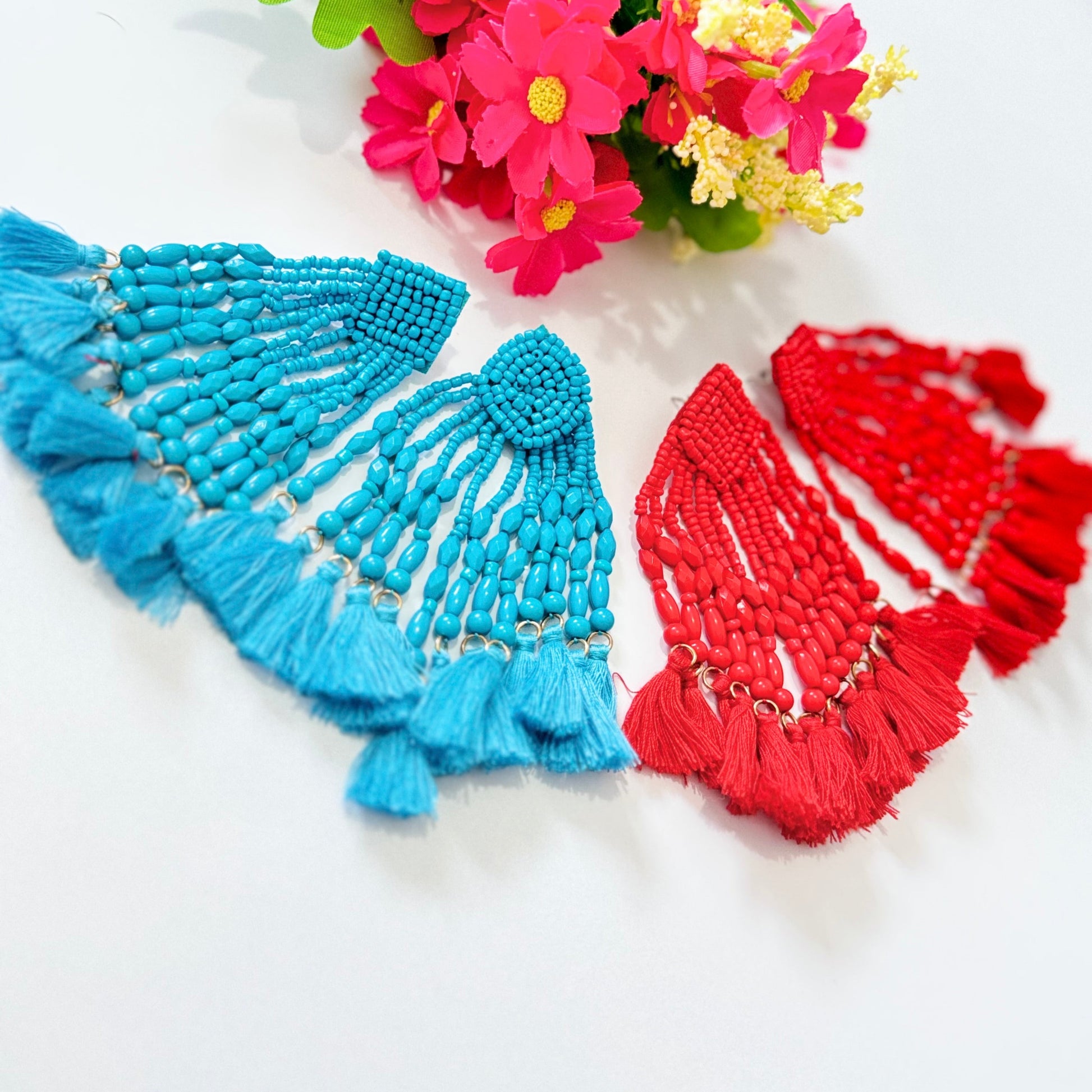  Crafted with intricate seed bead detailing and cascading strands of smooth, polished beads, these earrings exude a bold, eye-catching charm. The vibrant hues of turquoise and fiery red add a striking pop of color to any outfit, making them the perfect accessory for special occasions, beach vacations, or everyday glamour. 