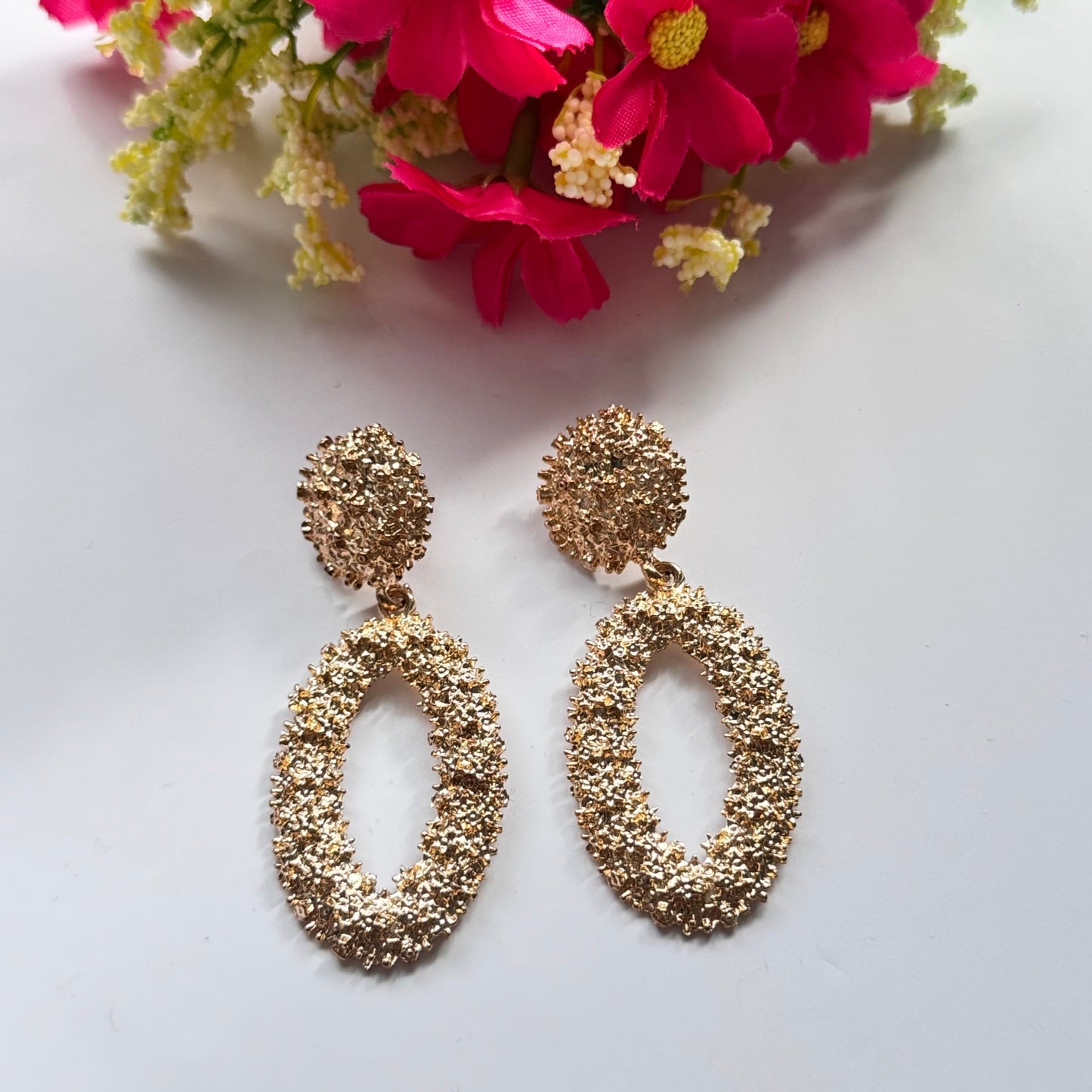 Dazzle in elegance with these stunning gold-tone textured earrings, designed to make a bold yet sophisticated statement. Featuring a unique organic finish that shimmers with every movement, these oval drop earrings bring a touch of luxury to any outfit.