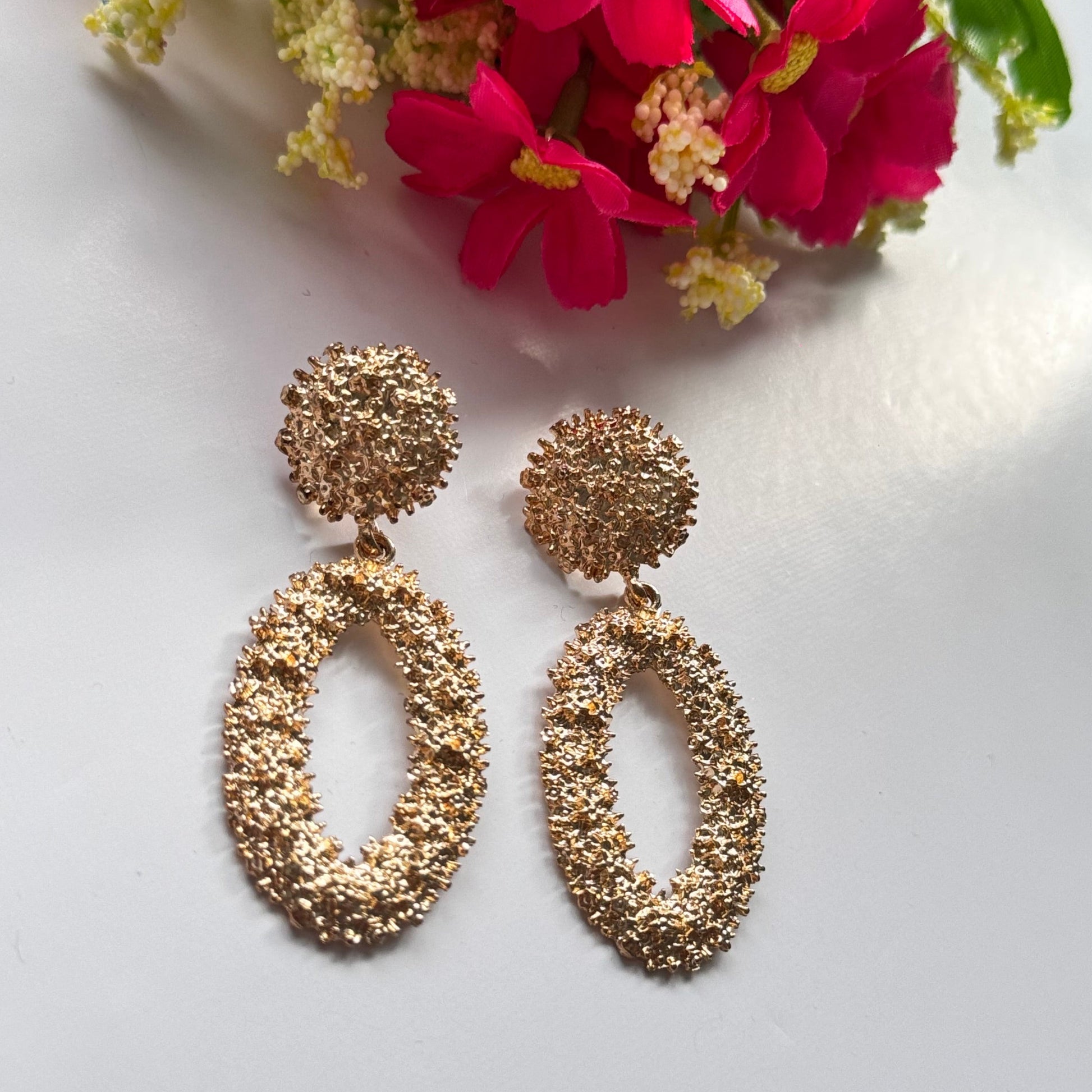 Dazzle in elegance with these stunning gold-tone textured earrings, designed to make a bold yet sophisticated statement. Featuring a unique organic finish that shimmers with every movement, these oval drop earrings bring a touch of luxury to any outfit.