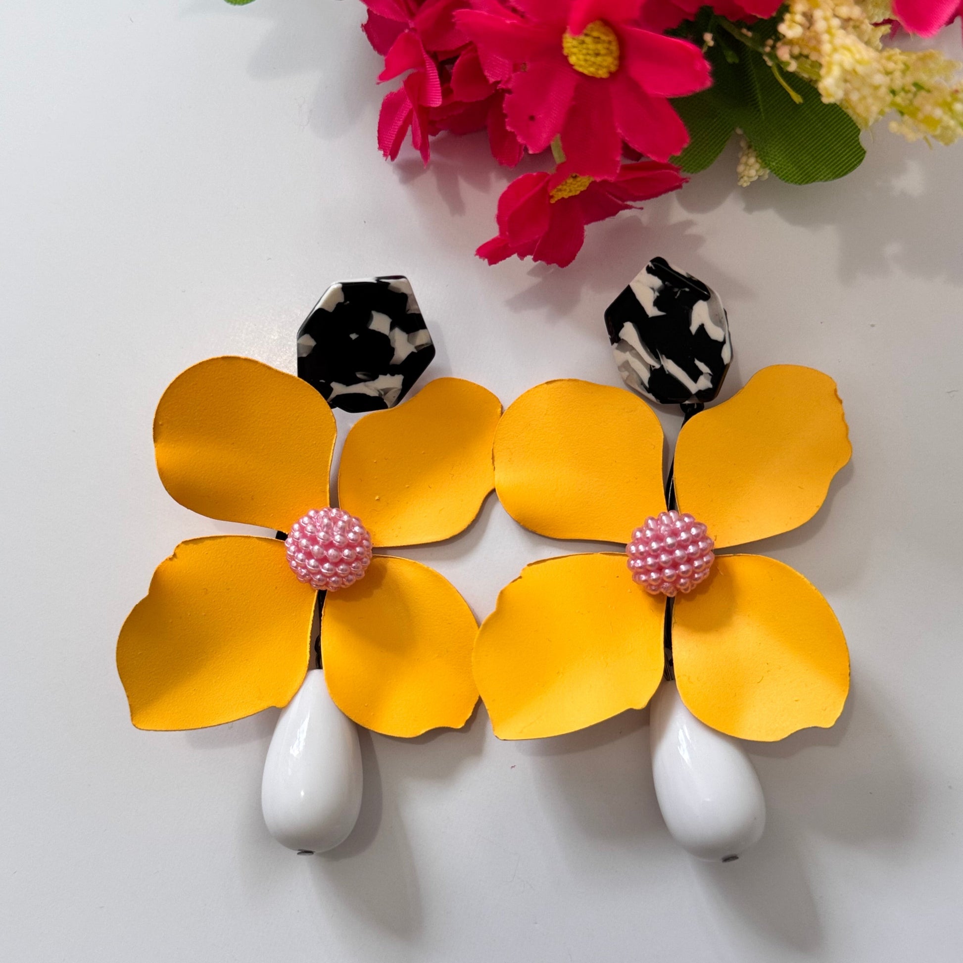 Add a bold pop of color to your look with these stunning floral drop earrings! hese earrings feature delicately sculpted flowers in rich hues of red, black, lilac, royal blue, and sunshine yellow, accented with textured centers for a playful yet sophisticated touch. 
