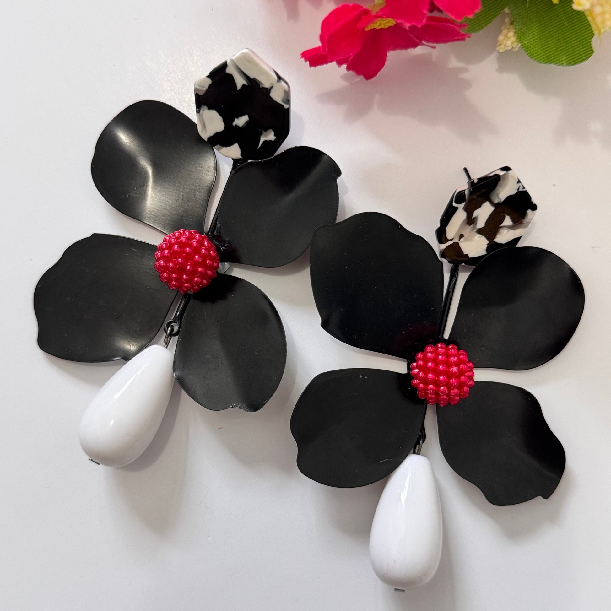 Add a bold pop of color to your look with these stunning floral drop earrings! hese earrings feature delicately sculpted flowers in rich hues of red, black, lilac, royal blue, and sunshine yellow, accented with textured centers for a playful yet sophisticated touch. 