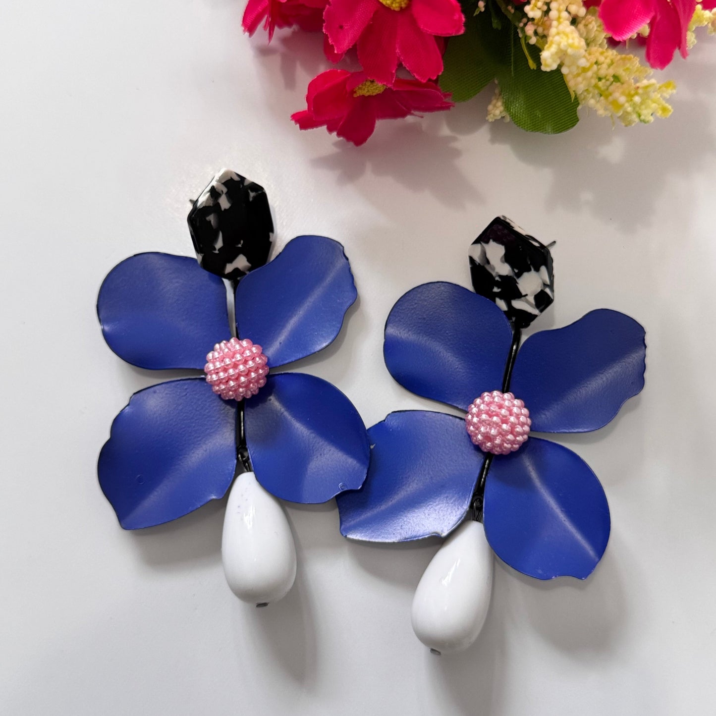 Add a bold pop of color to your look with these stunning floral drop earrings! hese earrings feature delicately sculpted flowers in rich hues of red, black, lilac, royal blue, and sunshine yellow, accented with textured centers for a playful yet sophisticated touch. 