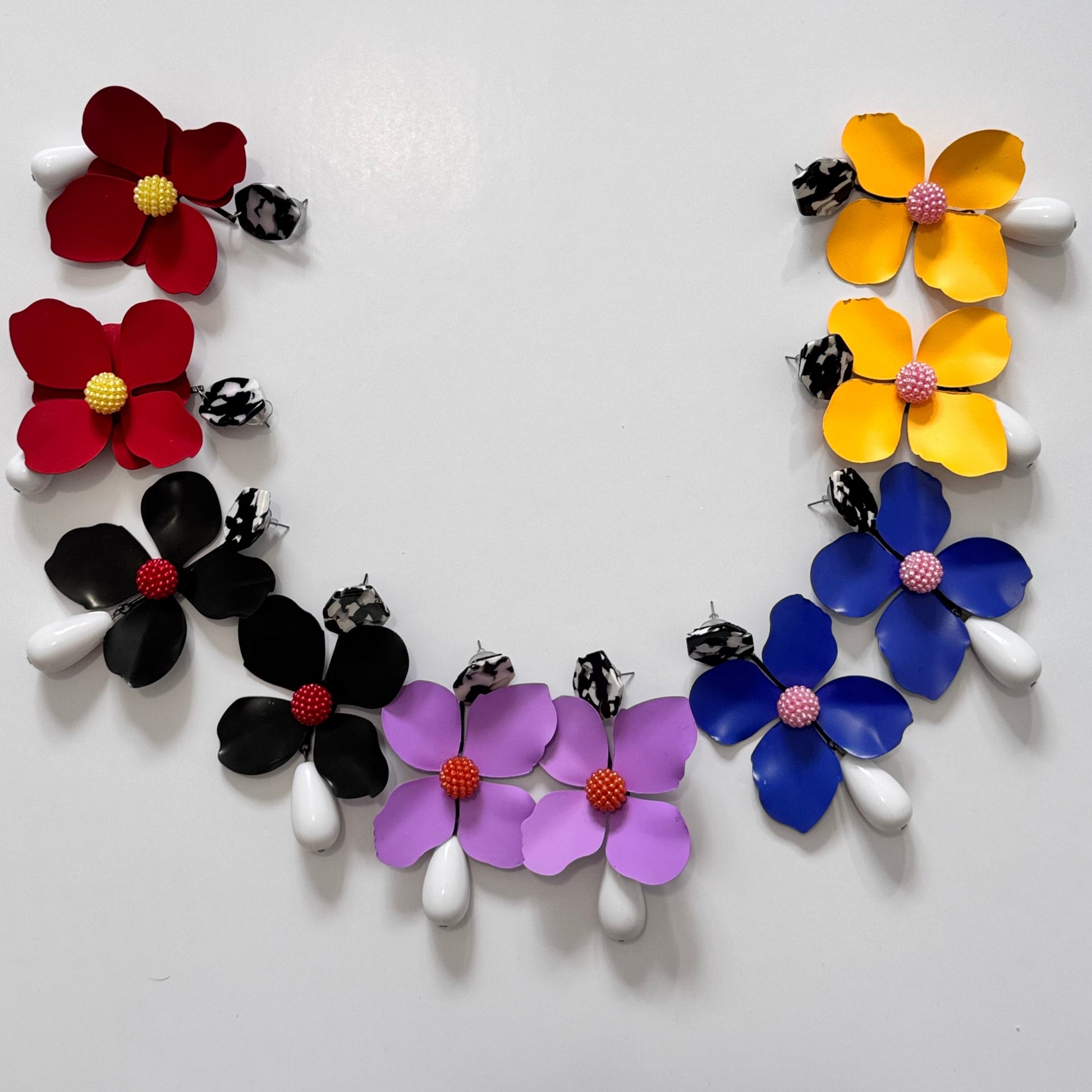 Add a bold pop of color to your look with these stunning floral drop earrings! hese earrings feature delicately sculpted flowers in rich hues of red, black, lilac, royal blue, and sunshine yellow, accented with textured centers for a playful yet sophisticated touch. 