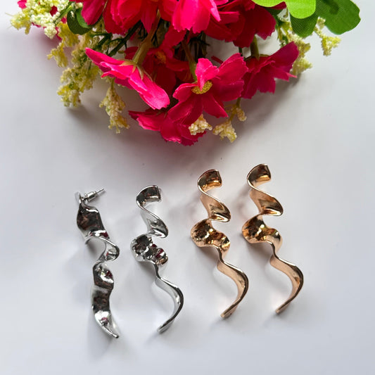 Elevate your style with these mesmerizing sculptural earrings, designed to turn heads and spark conversation. Featuring a stunning fluid wave design, these statement pieces are available in a radiant gold and sleek silver finish, each reflecting light beautifully to create a captivating shimmer with every movement. 