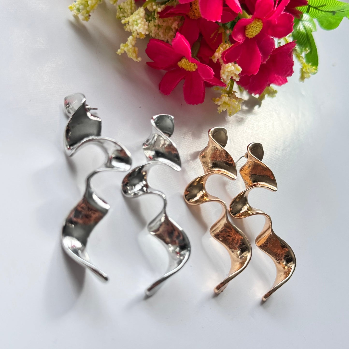 Elevate your style with these mesmerizing sculptural earrings, designed to turn heads and spark conversation. Featuring a stunning fluid wave design, these statement pieces are available in a radiant gold and sleek silver finish, each reflecting light beautifully to create a captivating shimmer with every movement. 