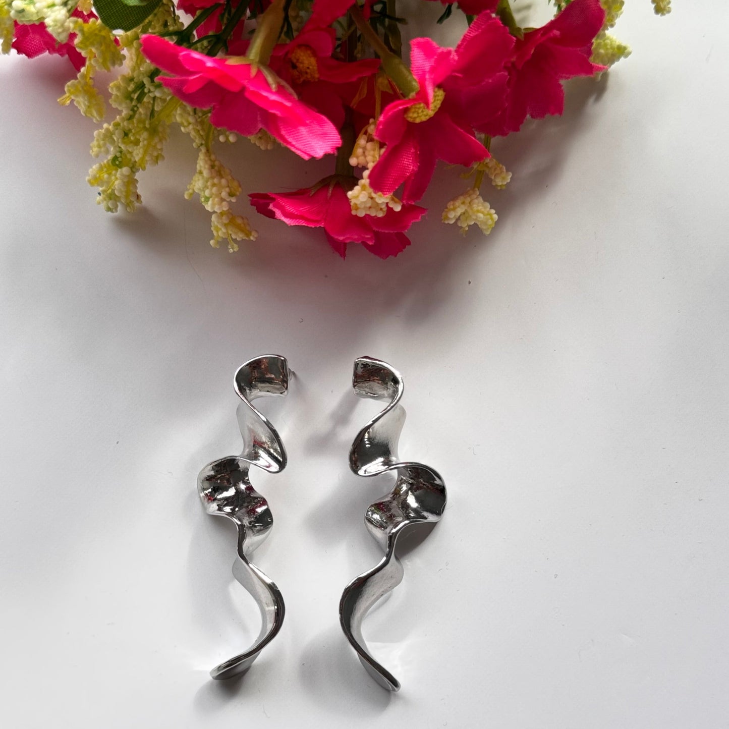Elevate your style with these mesmerizing sculptural earrings, designed to turn heads and spark conversation. Featuring a stunning fluid wave design, these statement pieces are available in a radiant gold and sleek silver finish, each reflecting light beautifully to create a captivating shimmer with every movement. 
