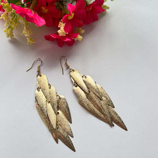 Stunning gold-toned statement earrings, designed to captivate and command attention. Featuring a cascading arrangement of textured metallic leaf-like elements, these lightweight yet bold earrings exude elegance, movement, and a touch of glamour.