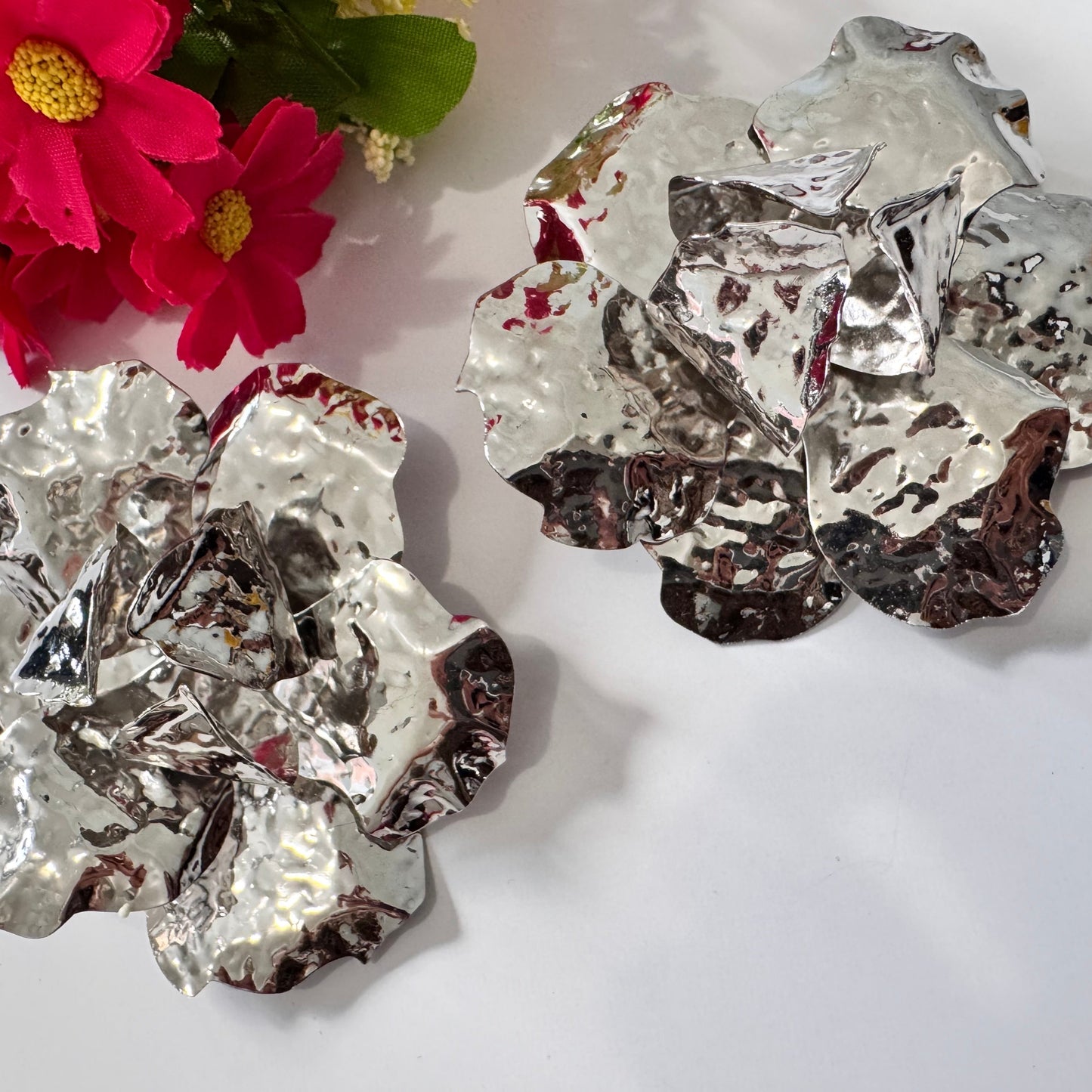 Dare to dazzle with these&nbsp;stunning Hammered Silver Floral Statement Earrings, a true showstopper for modern fashionistas! Crafted with a sculptural, textured metallic finish, these oversized floral earrings radiate contemporary glamour with an artistic edge