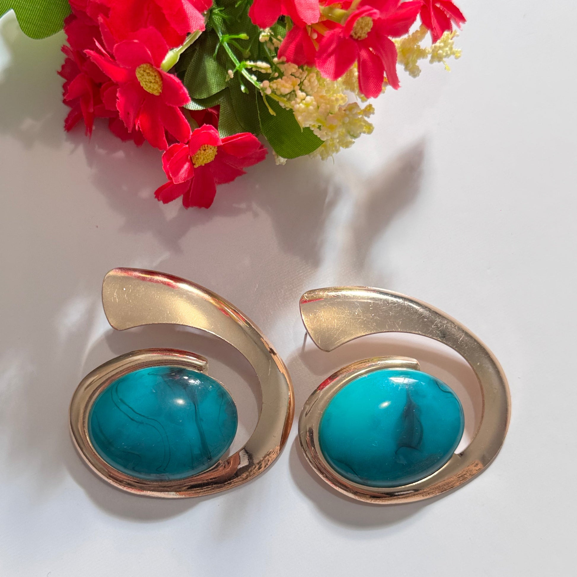 Exquisite gold and turquoise statement earrings, a perfect blend of elegance and boldness. Designed with a unique swirl-inspired gold frame, these earrings showcase a stunning oval turquoise stone with natural marbled veins, adding a touch of bohemian luxury. Whether you're dressing up for a special occasion or adding a chic accent to your everyday style, these earrings are the ultimate fashion-forward accessory. Vintage-inspired yet modern aesthetic.